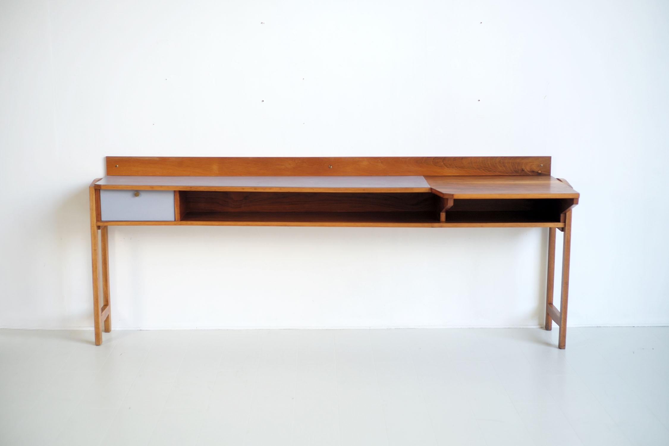 Console-desk in walnut and formica, Ventimiglia 1955. Perched on a portico base, this large console is trapezoidal in shape. On the left, a housing with a tilting door is veneered with yellow formica, the top, covered with gray formica, is lined in