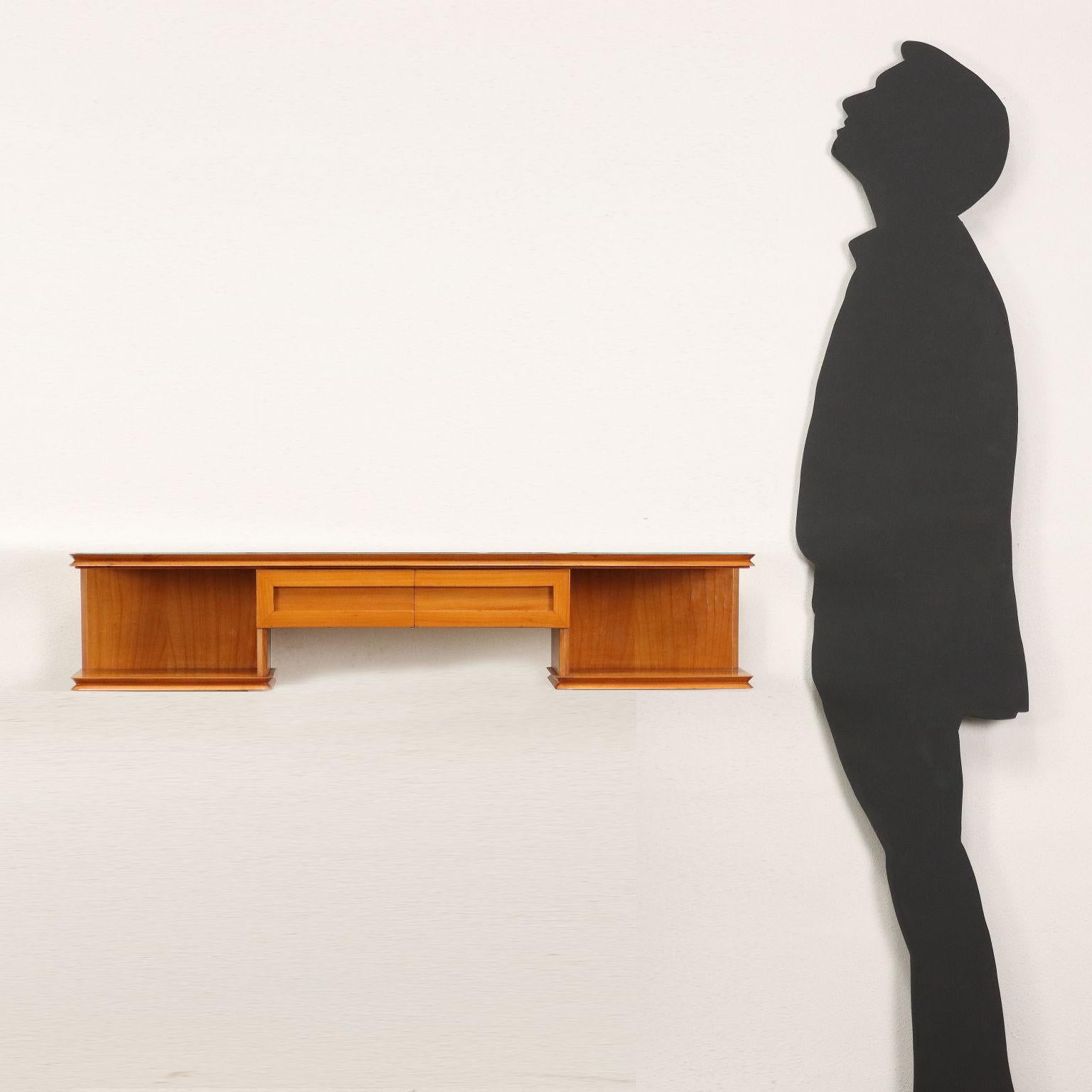 Hanging console with wall anchoring, visible drawers and open compartments; maple veneered wood, glass resting on the top.