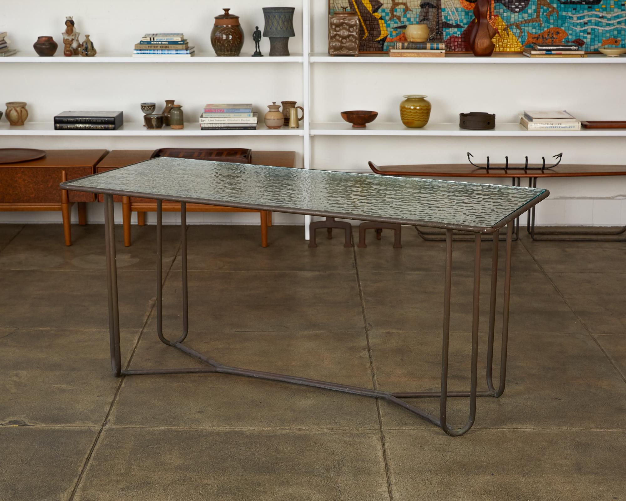 A narrow dining or console table in patinated bronze designed by Walter Lamb and produced by Brown Jordan. The table has a rectangular shape with rounded corners, supported by four hairpin legs in matching bronze. The legs are joined by diagonal