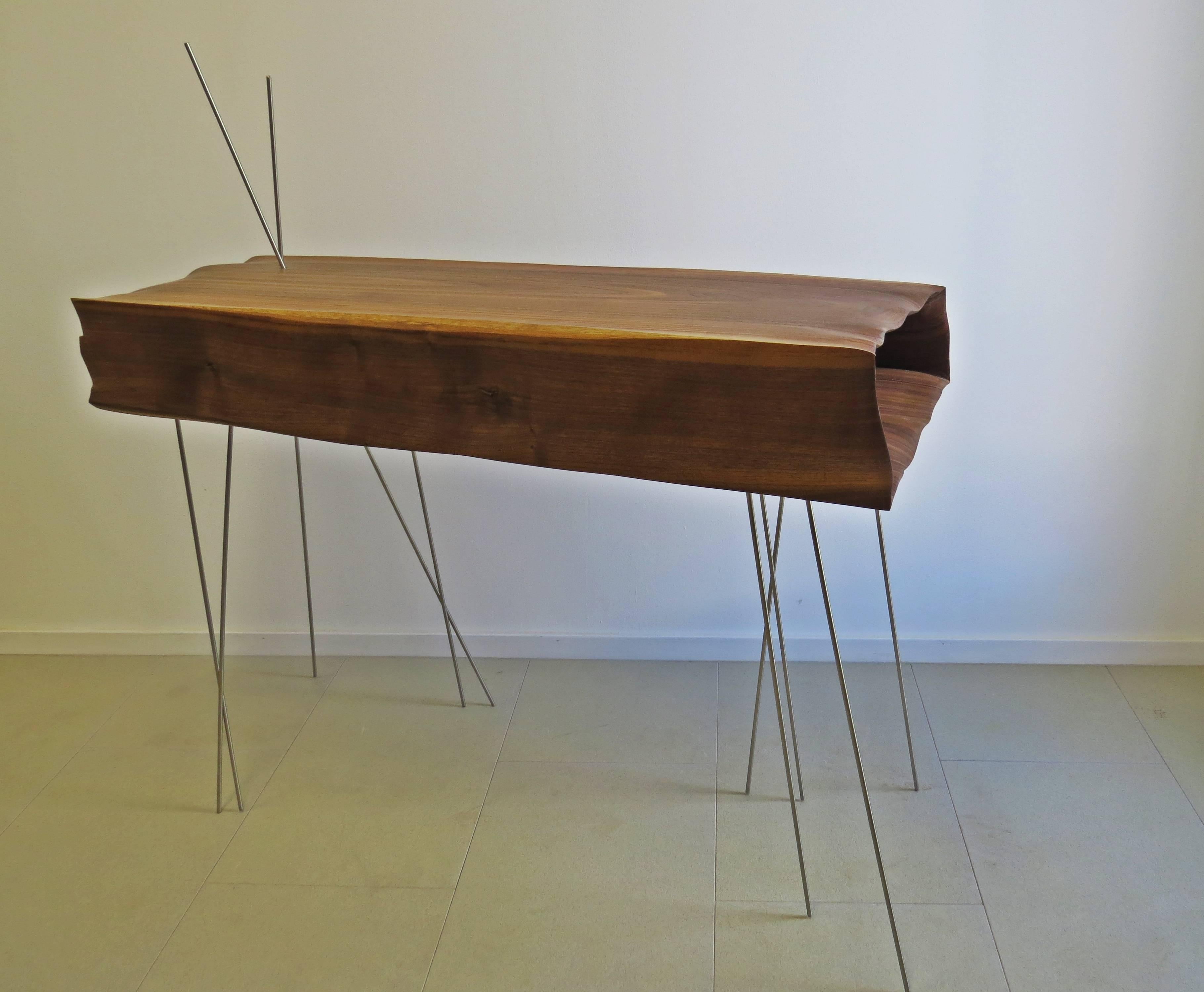 Console more sculpture like furniture.
The organically shaped hollow body is floating.
The wood is sculpted with folds and creases.
The thin stainless steel rods complete the overall picture and serve as legs.

Of course handmade, each part