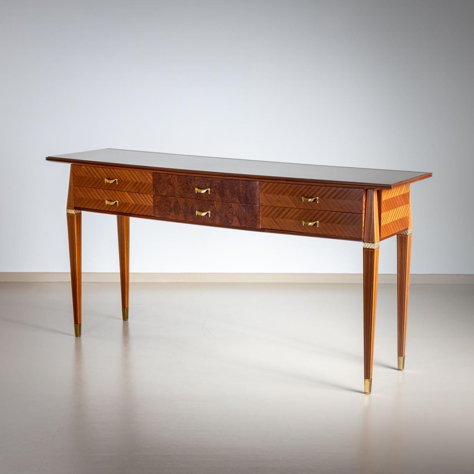 Italian console table on elegant square tapered legs with six drawers and brass sabots. The surface is fitted with an embedded glass panel and backed in gold. The front is decoratively inlaid in herringbone parquetry.