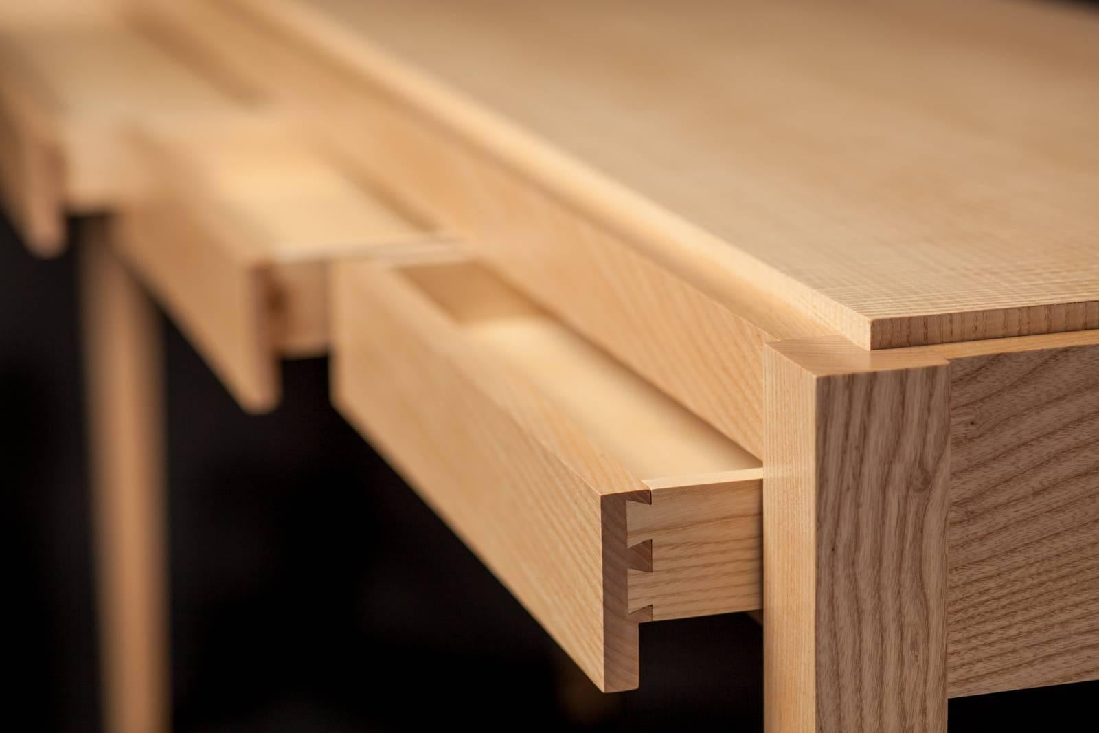 Raised inset top highlights stunning bookmatched figured ash veneers.
Quarter sawn solid white ash grain creates continuous crisp horizontal lines around the console.
Rift sawn solid white ash legs taper to accentuate a light feel.
Dovetail drawer
