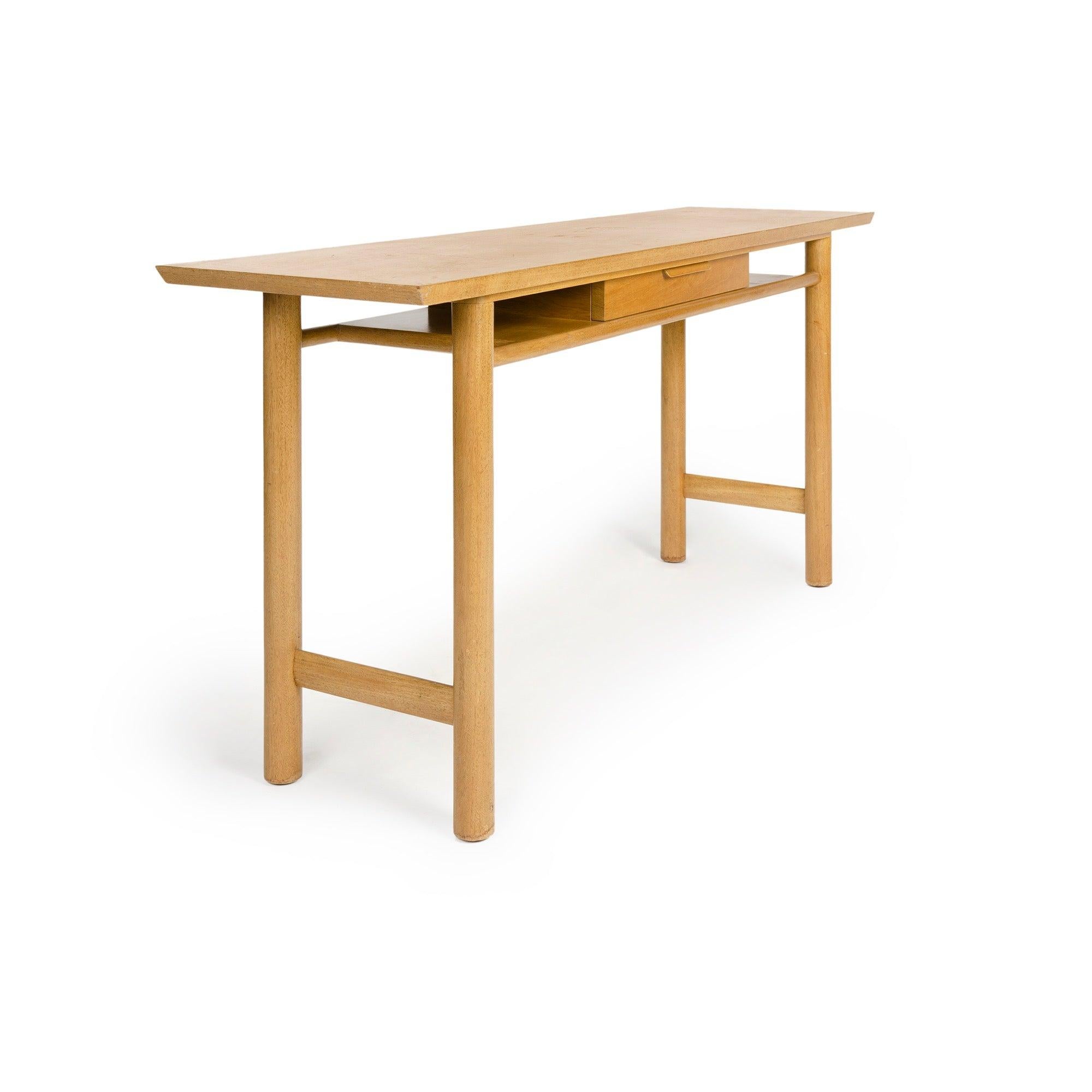 A bleached walnut and mahogany console table with drawer having a laminated pull, flanked by open shelves, on ?turned dowel legs.