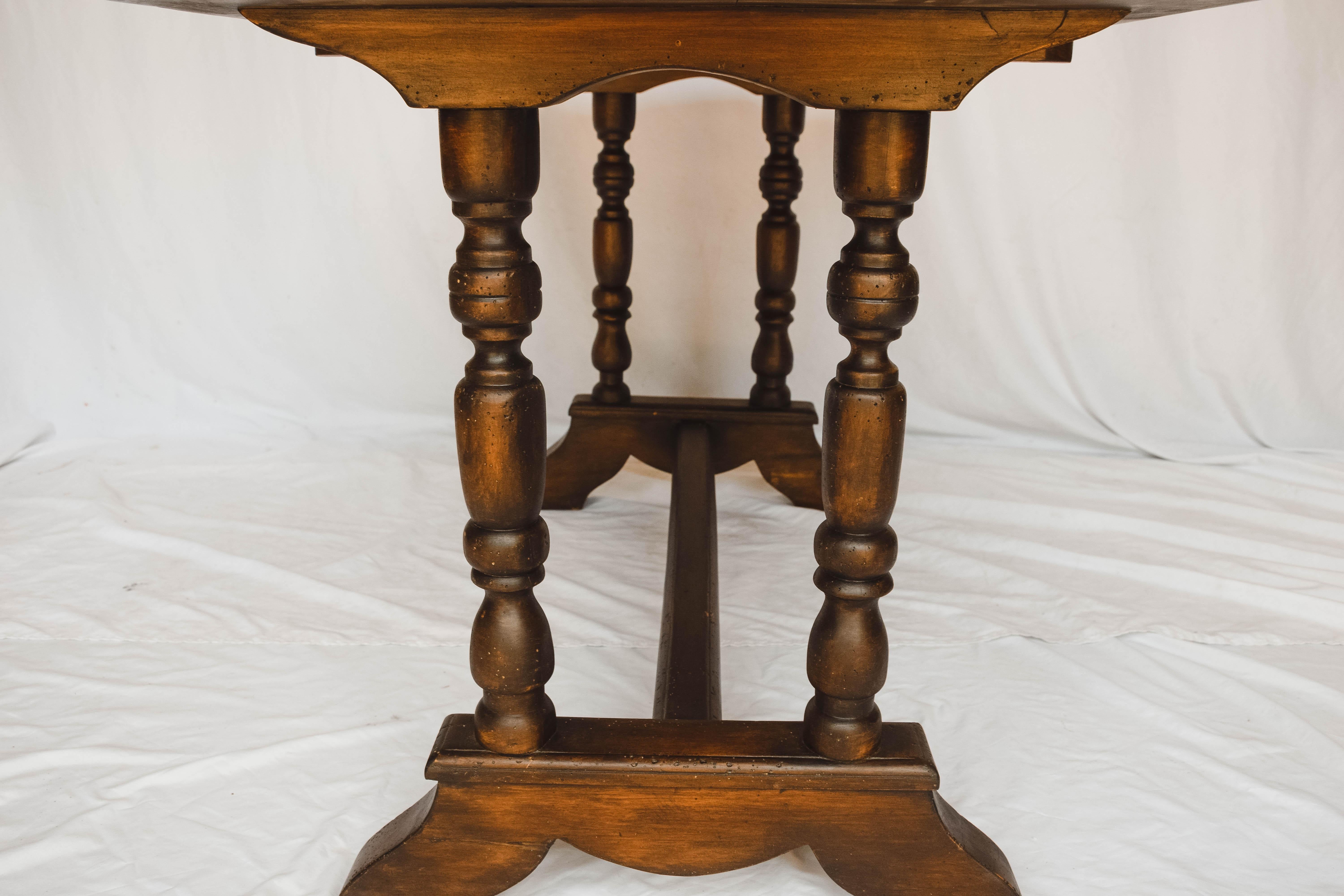 Fantastic wood console table with with trestle base and turned legs. This table finished in a dark stain and would be perfect in an entry. It could also be used as a game table or a perfect place to do a puzzle.