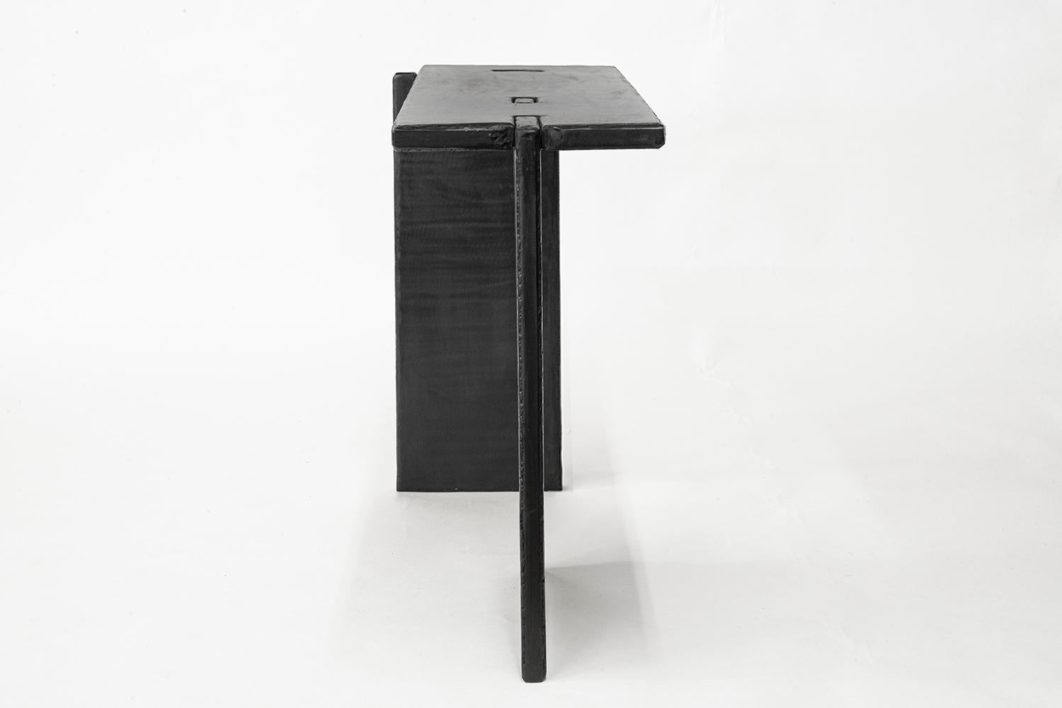 Console n° 5
A&M. Szymanski
d. 2022

Cette console est composée de plans austères et perpendiculaires qui ont été entaillés et assemblés avec précision. Ses bords bruts sculptés à la main contrastent magnifiquement avec les surfaces planes continues