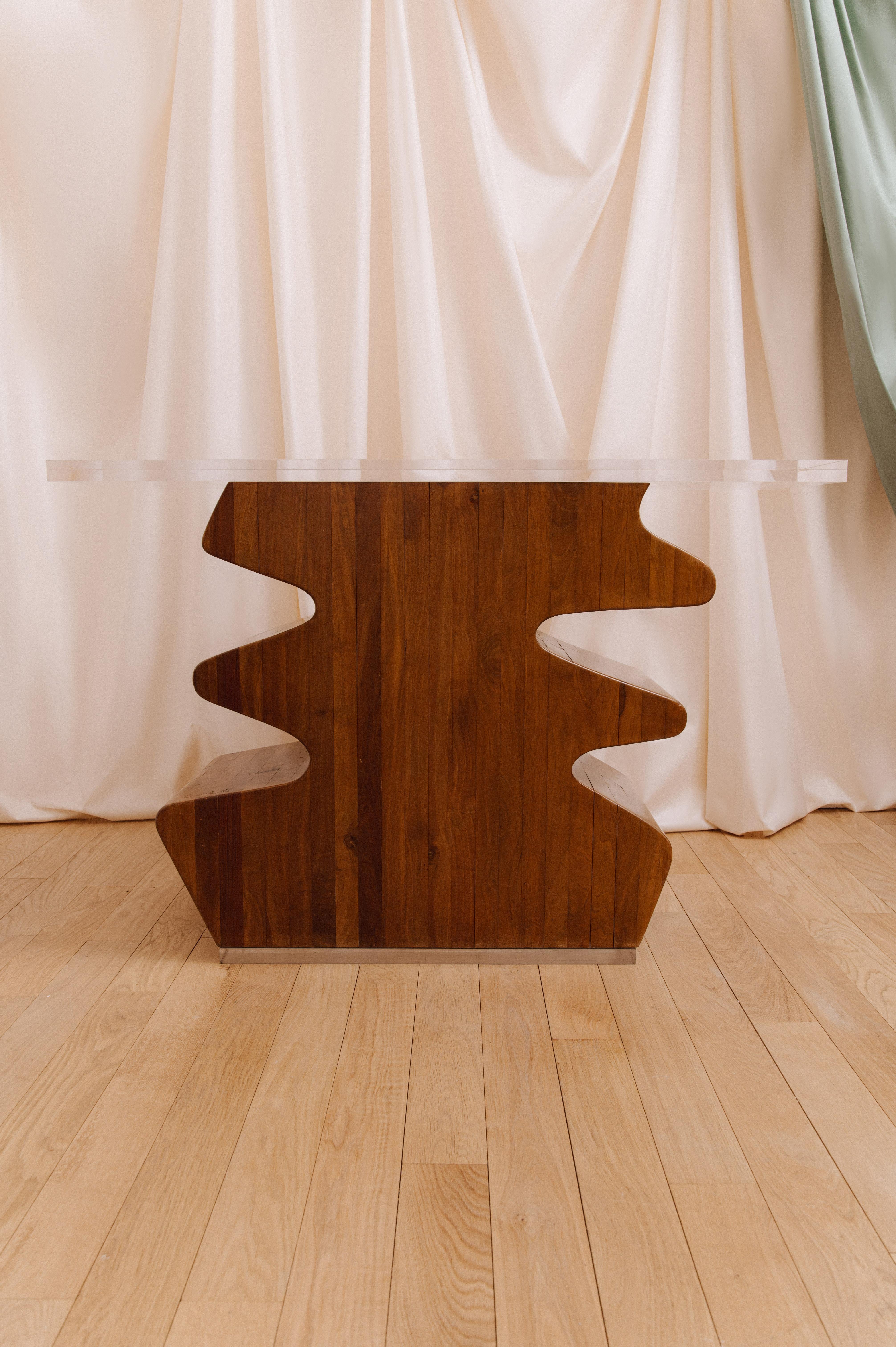 Skulpturenkonsole aus Holz von Guasti Marcello mit einer Platte aus Méthacrylat, 1980. Signatur des Künstlers im Holz eingraviert. 
Das Noyer-Möbel hat ein sehr skulpturales Design mit geraden Linien und Dekorationen, die ihm eine organische