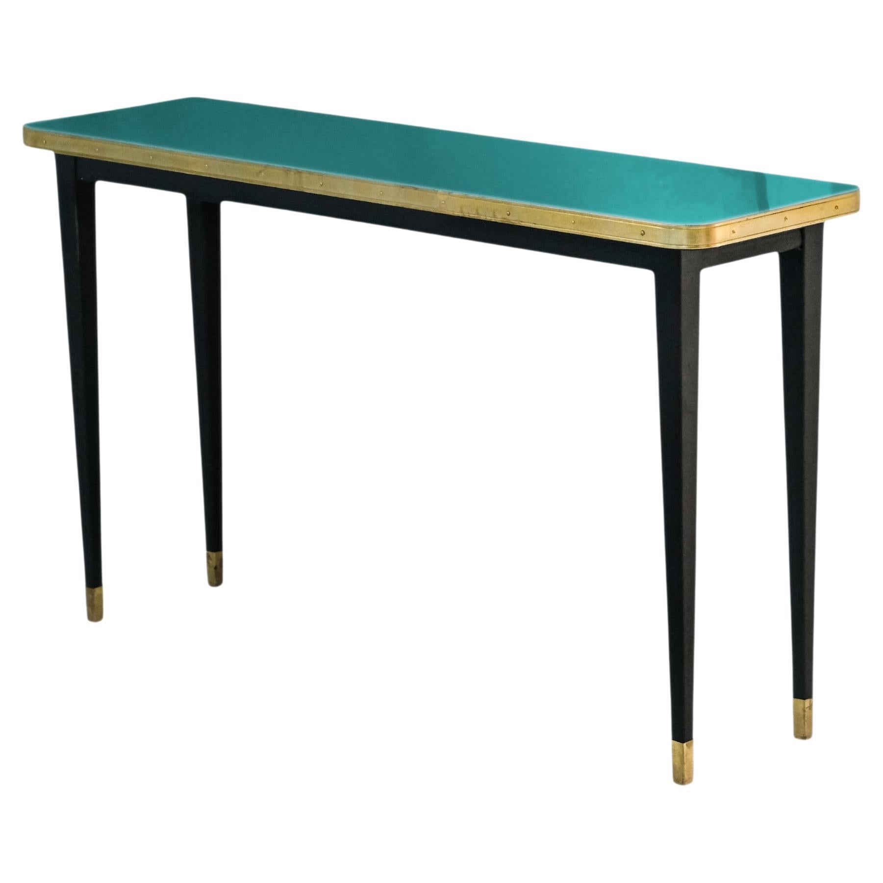Julieta Collection. 

Console Table with High Gloss Top, Brass Tape Framed, Black Powder Coating Conical Legs with Brass End

Introducing the stunning console table with black powder-coated steel construction, boasting sleek conical legs with brass