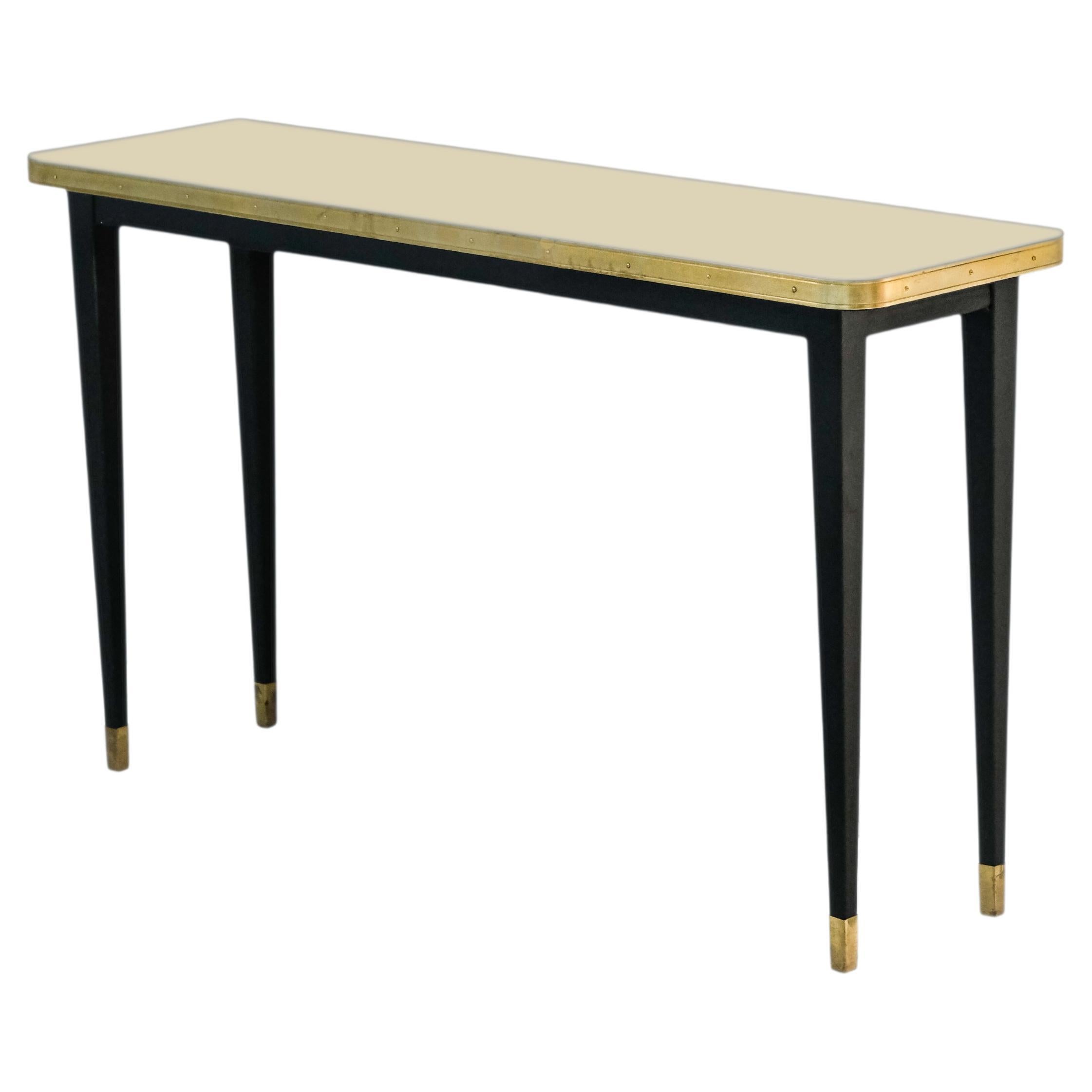 Julieta Collection. 

Console Table with High Gloss Top, Brass Tape Framed, Black Powder Coating Conical Legs with Brass End

Introducing the stunning console table with black powder-coated steel construction, boasting sleek conical legs with brass