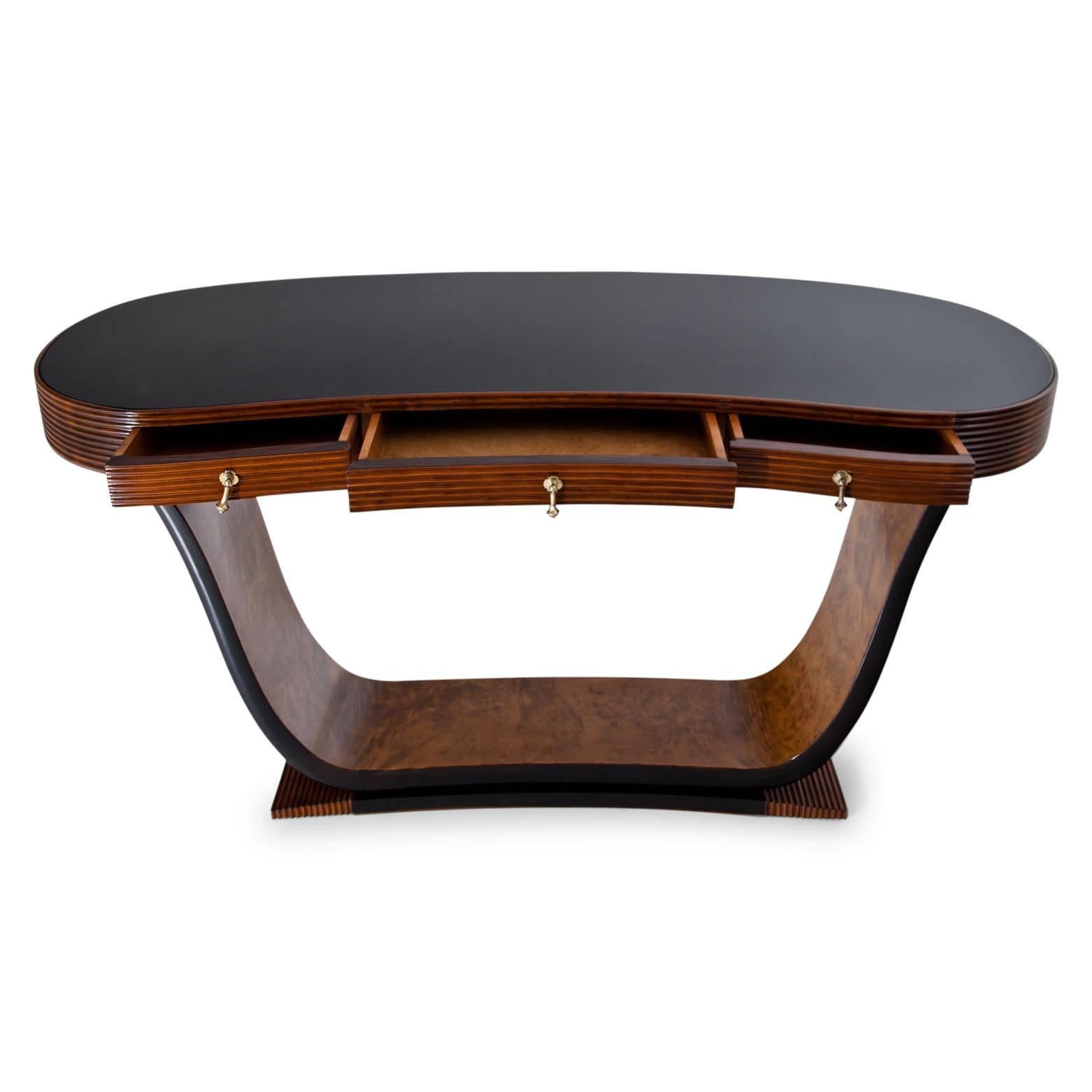 Kidney-shaped console table with a black glass tabletop, standing on a tulip-shaped base. The body shows horizontal groves and has three drawers. The console is in a professionally refurbished condition.