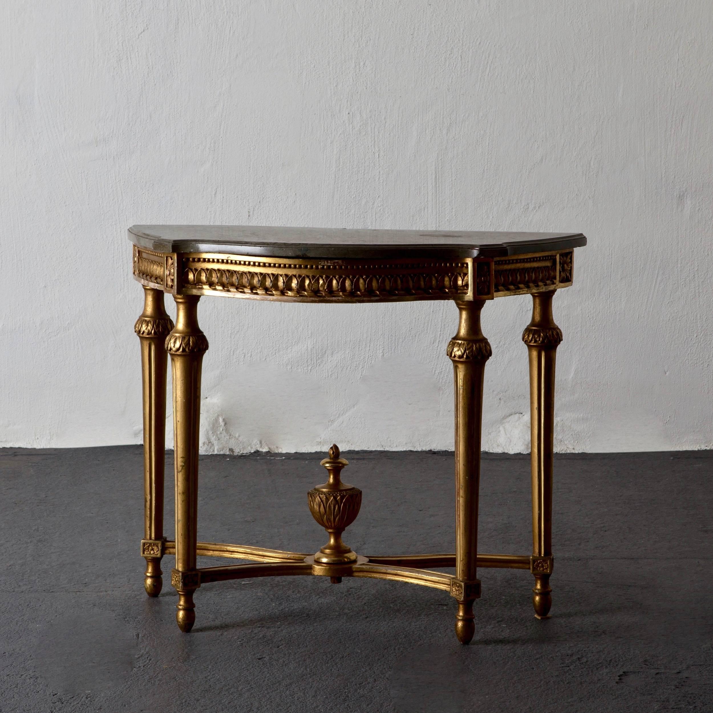 Console table Swedish Gustavian period, Sweden. A high Gustavian console table in giltwood with an original lime stone top. Fluted legs tied together with a foot cross carrying an leaf tip carved urn.