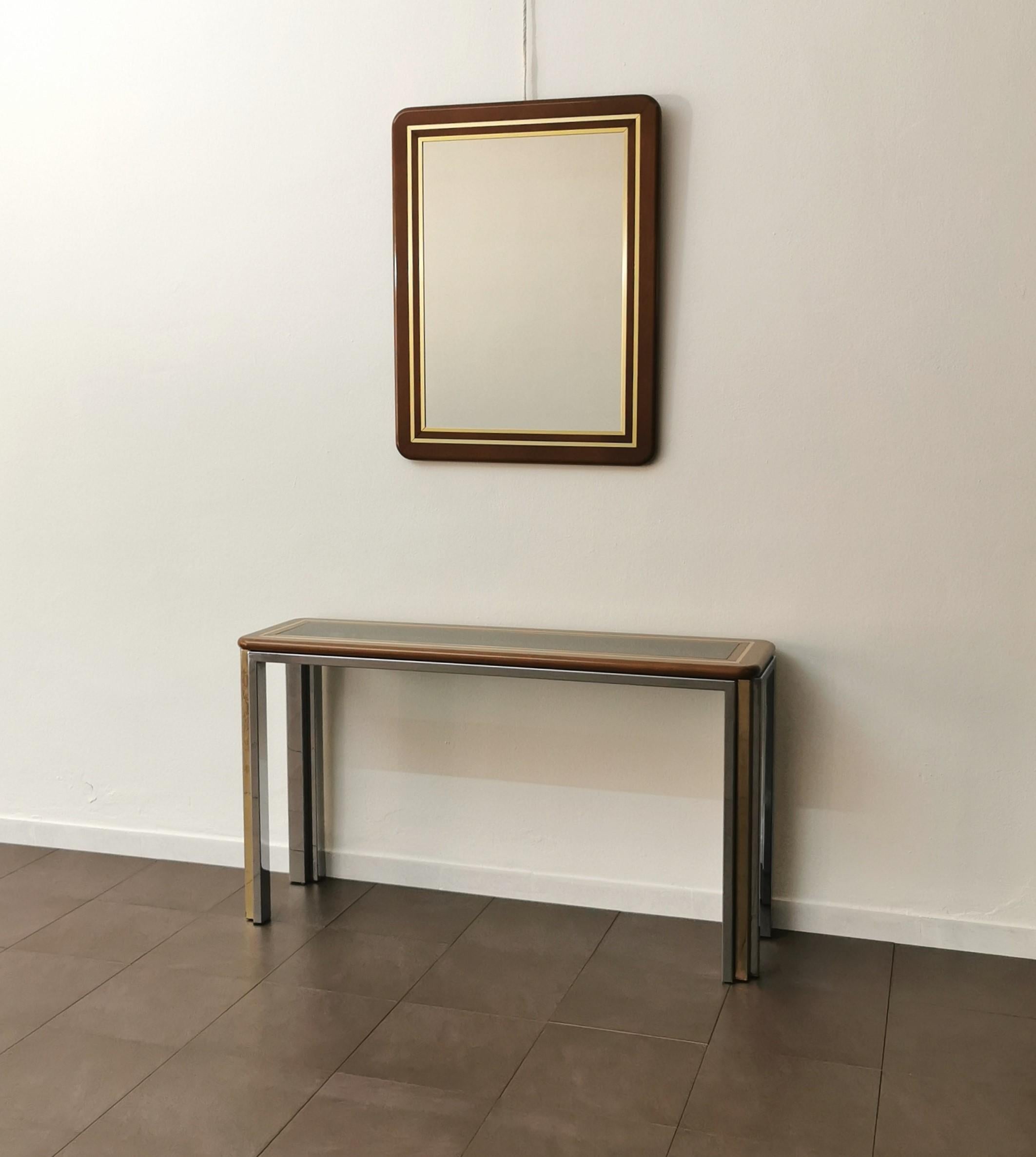 Set of a console and a wall mirror produced in Italy in the 70s. The console was made with a 4-legged structure in chromed and gilded metal and with a rectangular top in wood and gilded aluminum, where a smoked glass is placed above it. The mirror