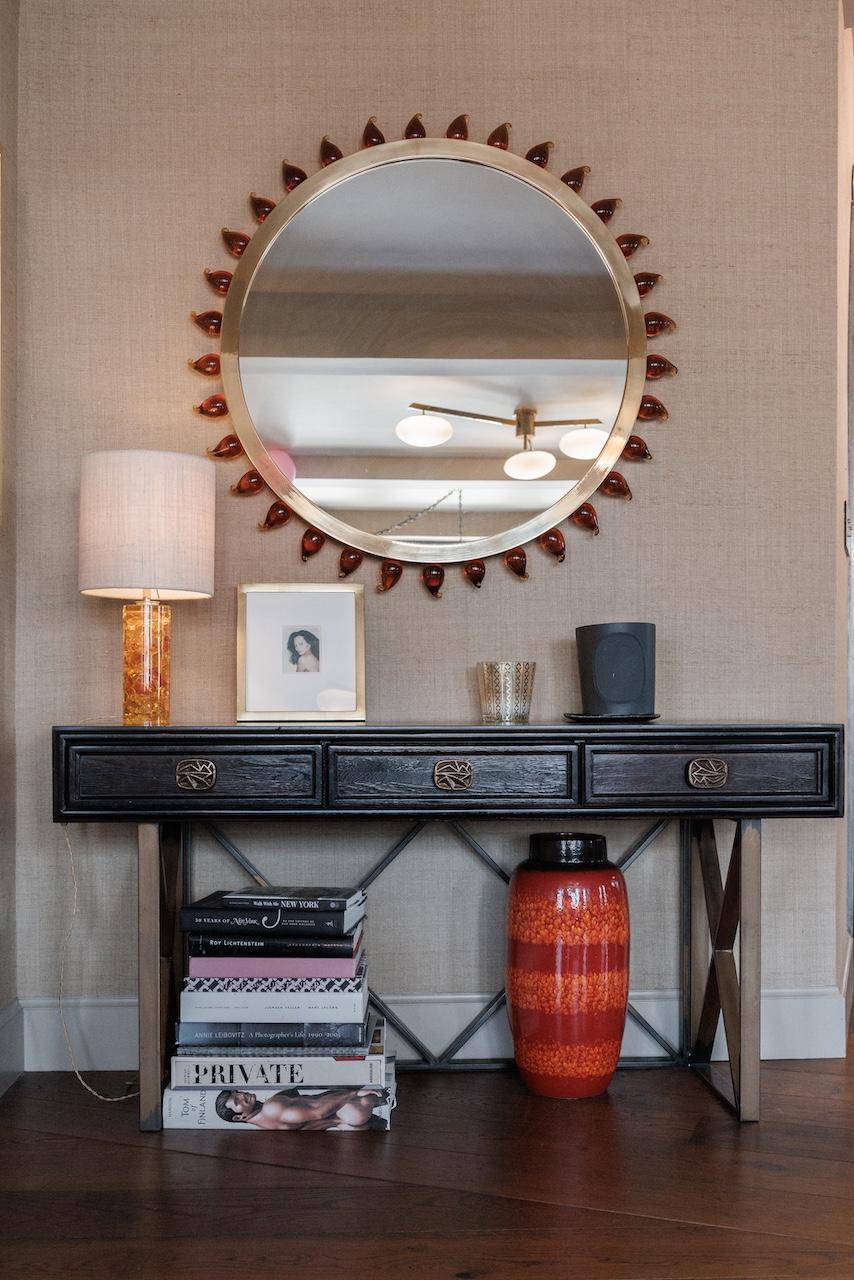 This console table from ABC Modern features a dark wooden top with three drawers, supported by a metal base with an X-shaped design. 

Andy Cohen is a longtime supporter of Housing Works and has generously donated this exclusive item from his