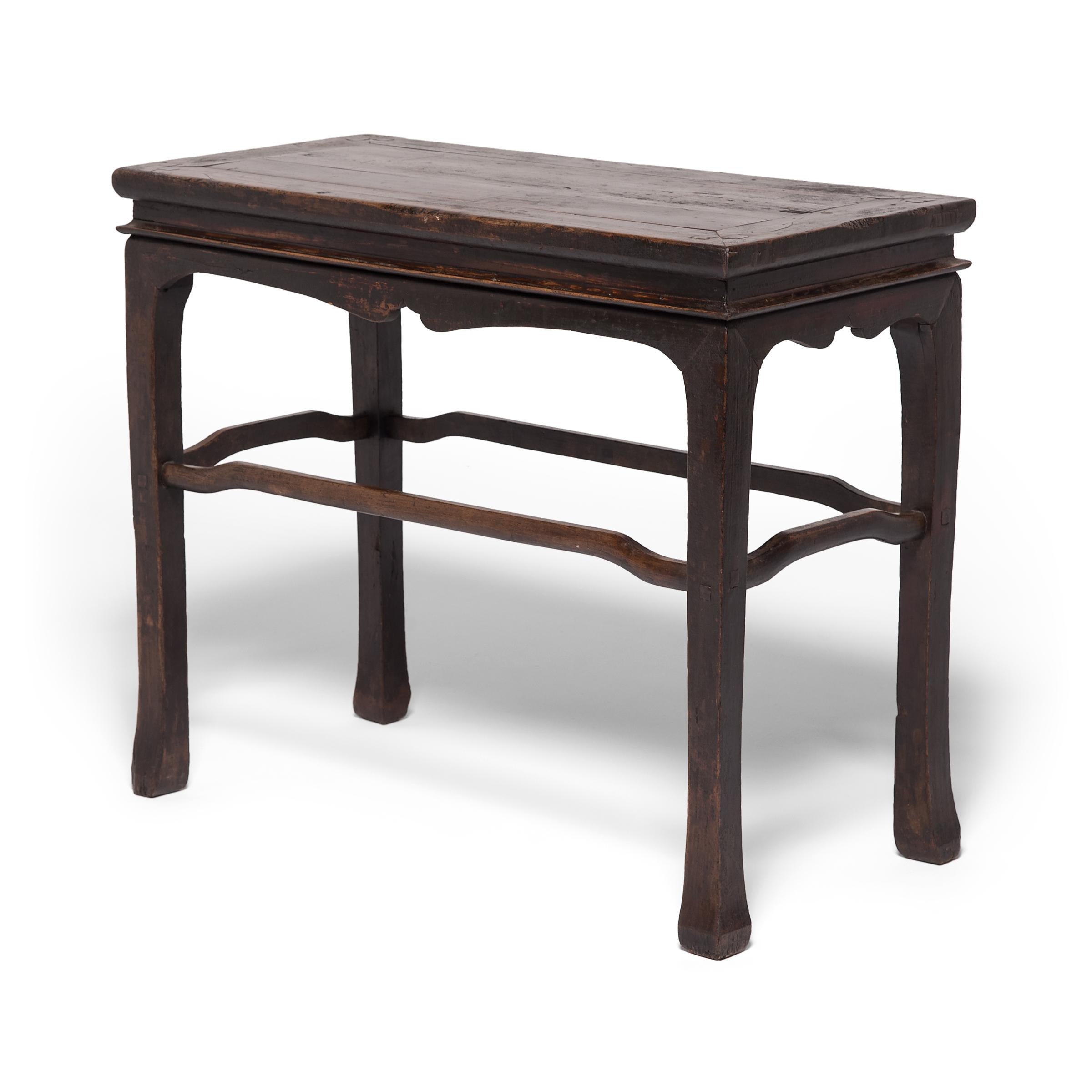Handcrafted of northern elmwood over a century ago, this simple wine table expresses the clean lines and elegant restraint that make Qing-dynasty carpentry so sought after. Emphasizing the table's refined form, a simple scalloped apron flows into