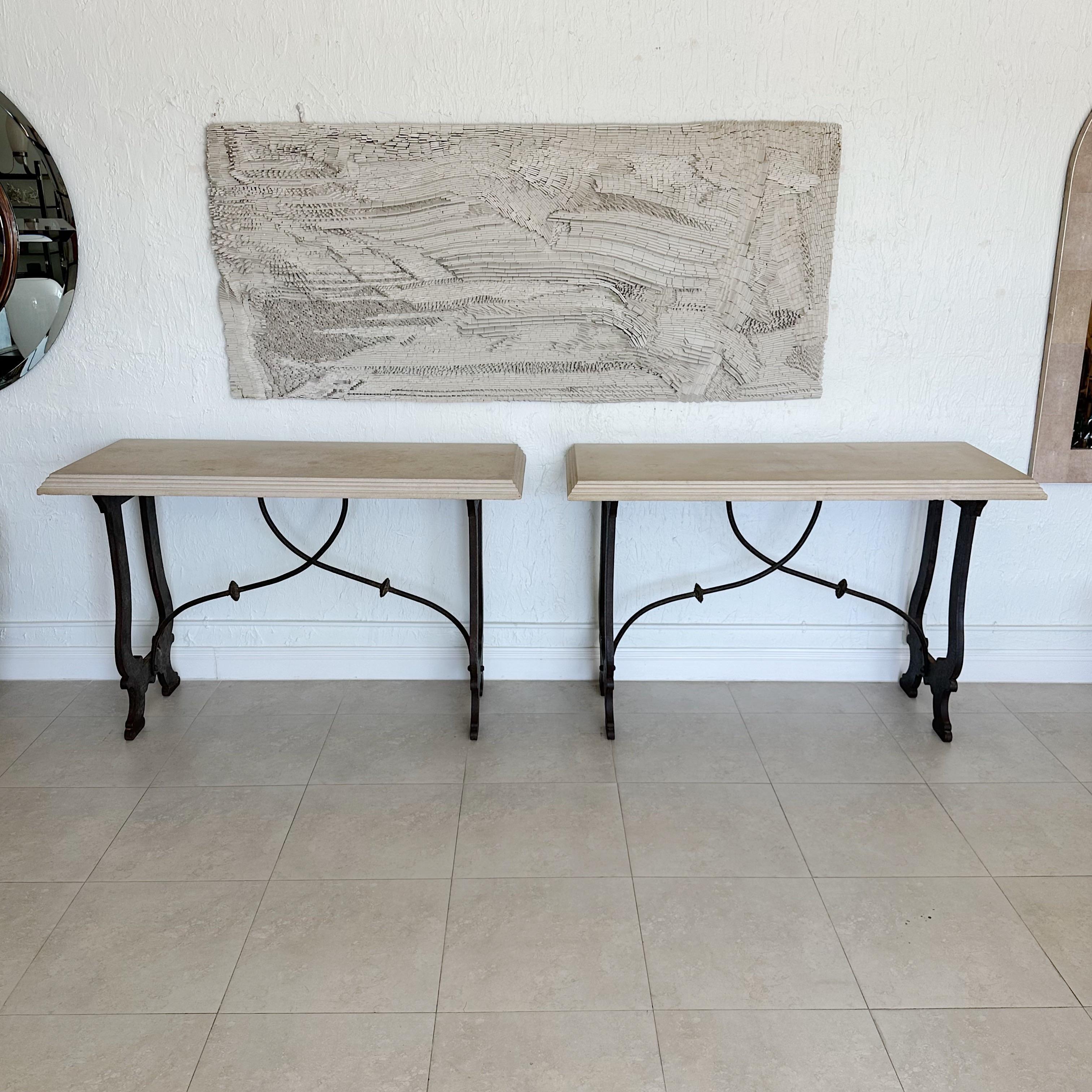 Pair of consoles tables that boast a sandstone top and iron harp-shaped support ends. This table is connected by wrought iron supports that add to its unique appearance. These stunning pieces are inspired by 18th century design. The sandstone tops