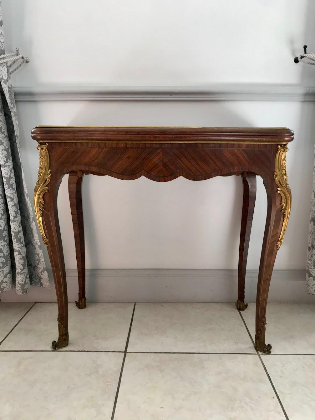 Nice console that unfolds to form a game table dating from the 19th century. 
This nice piece of furniture is in the Louis XV style, it has 4 curved legs. It is totally made of marquetry. These legs are dressed with brass falls with plant motifs and