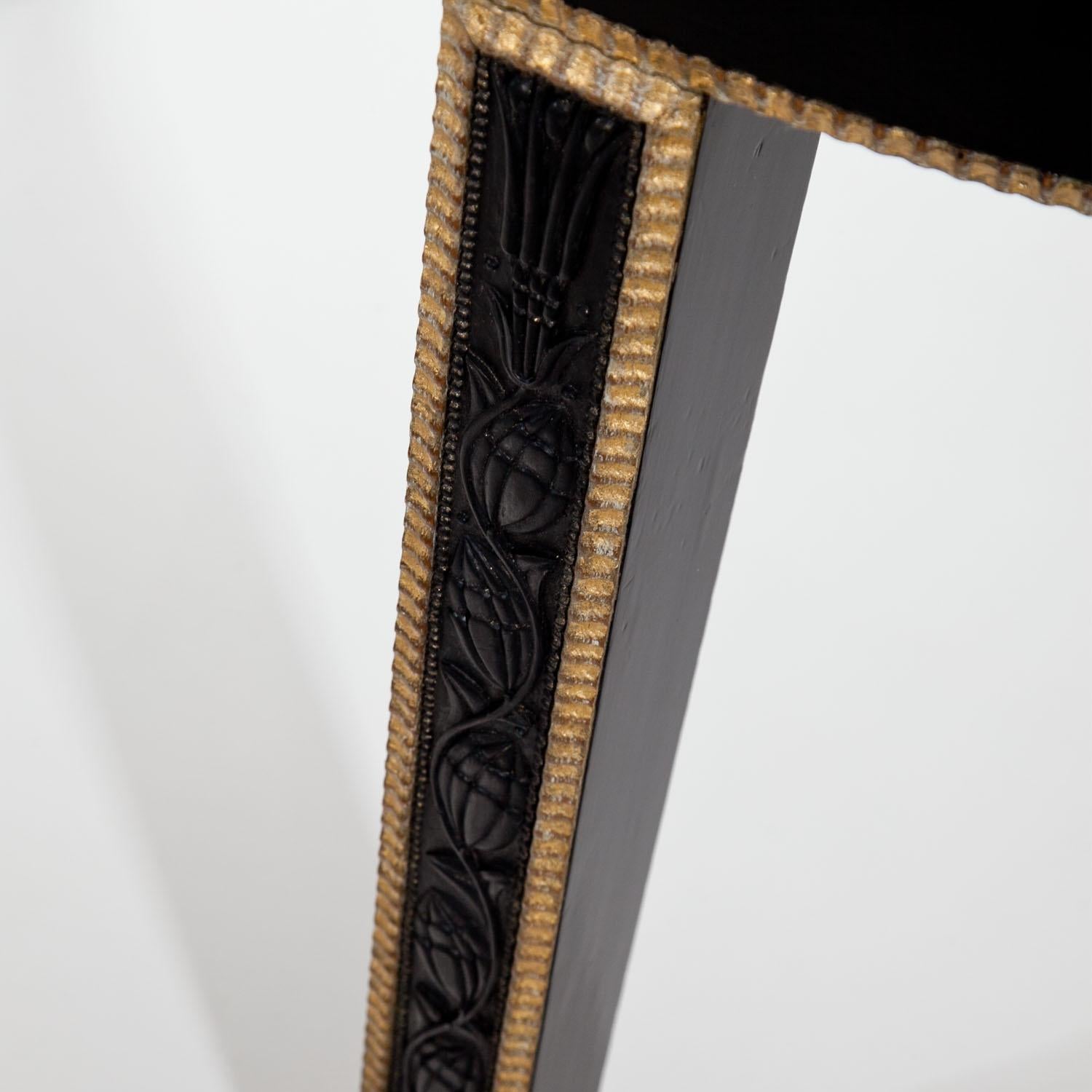 Ebonized demilune console table of the Vienna Secession, standing on three legs. The straight apron and the legs are decorated with gilt wavy profiles, the latter also with carved flowers and vines at the front. The glass top is recent.