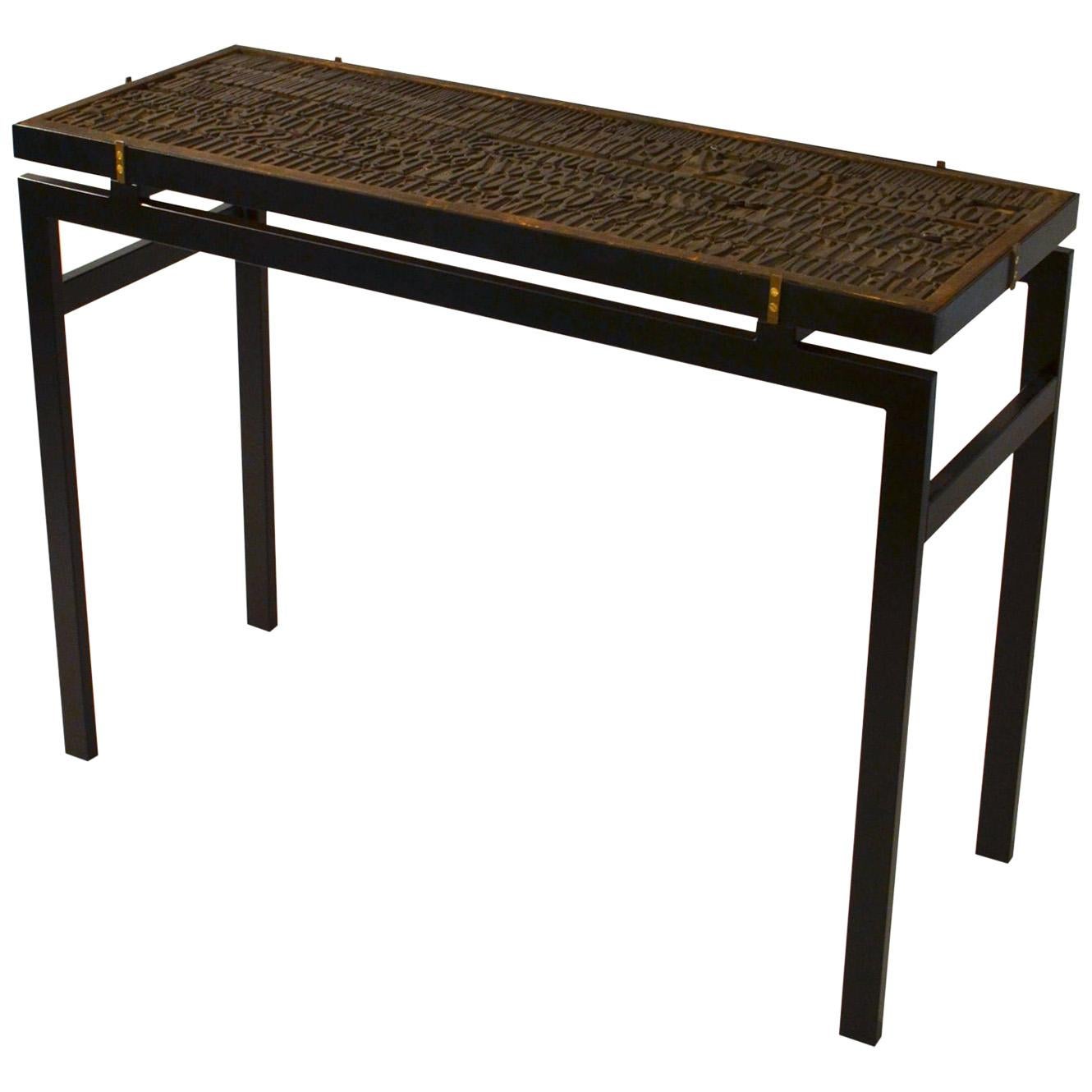 Consola con relieve de letras impresas y tapa de cristal sobre marco de metal negro Tallado a mano en venta