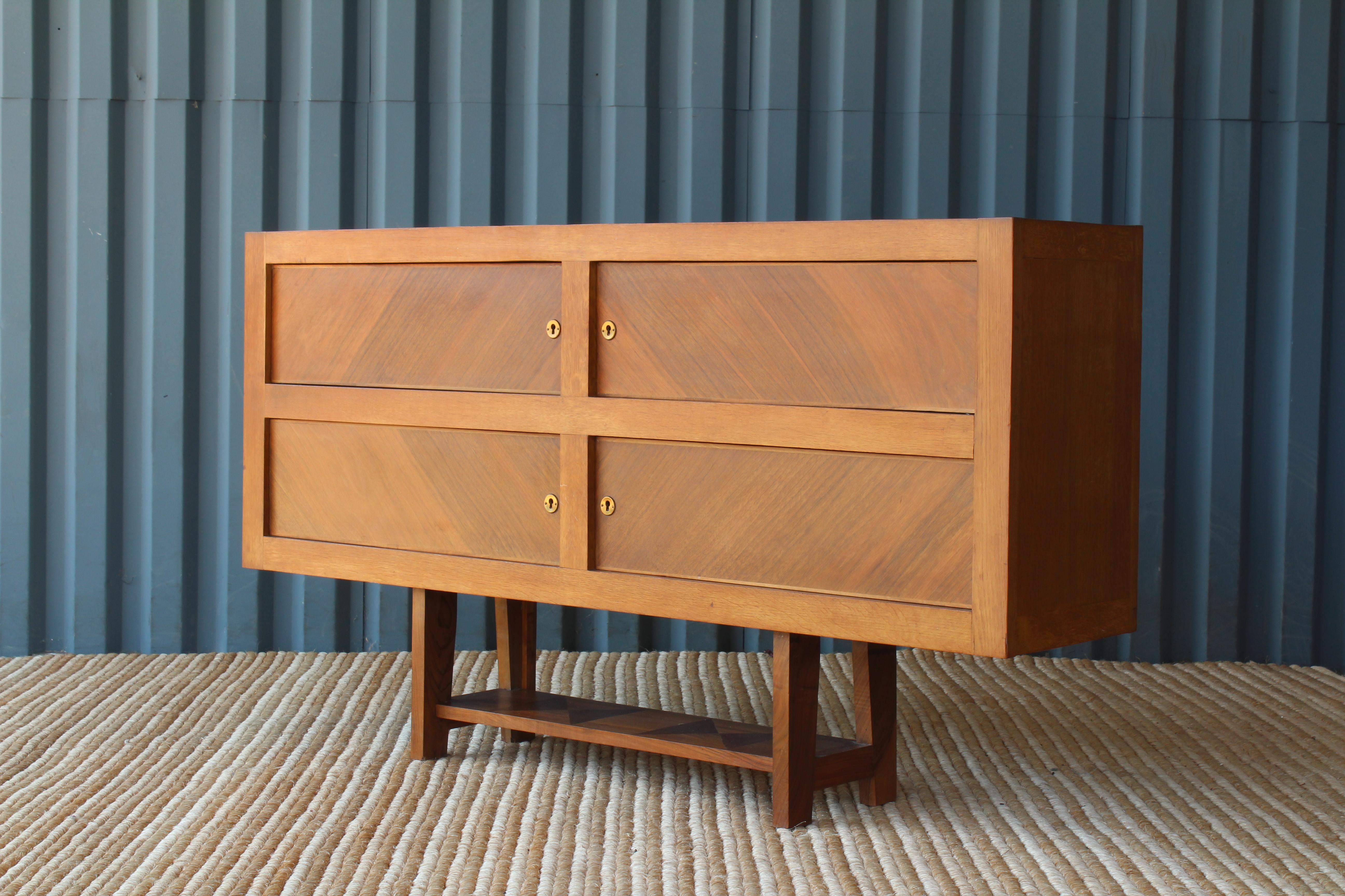 One of a kind vintage console with four locking doors. Contrasting grain on doors and a parquet wood detail on the lower shelf. Newly refinished. Includes original brass keys.

 
