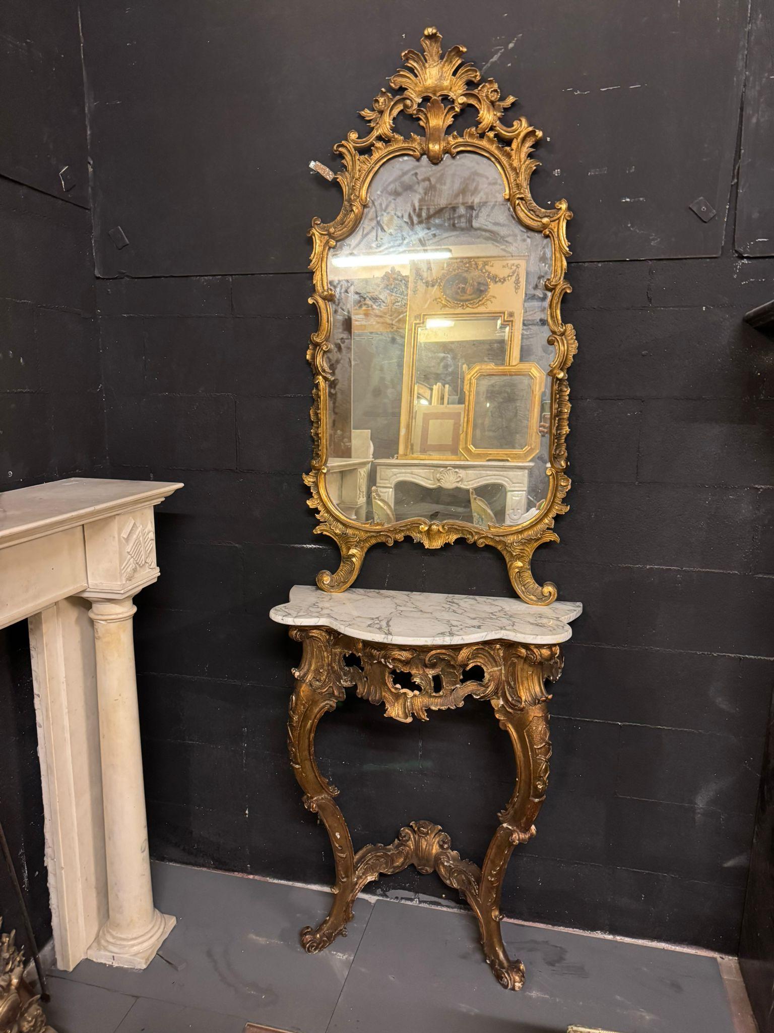 Antique Console, support with mirror in carved and gilded wood and base table. This console has a white marble top with darker veins, the band is richly carved and perforated with leafy scroll decorations and plant elements, two arched legs always