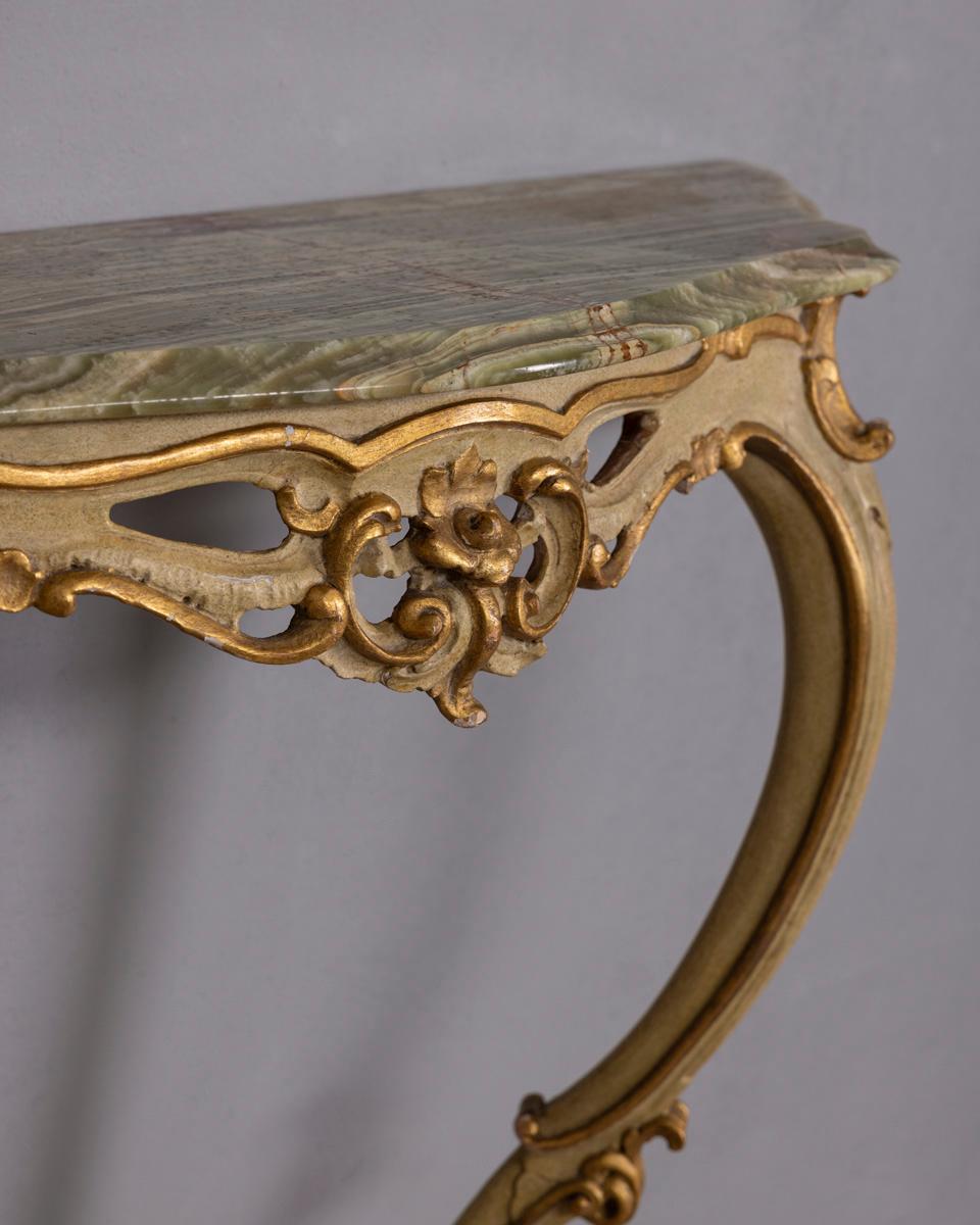 Consolle da parete con cornice in legno intagliato color oro e crema, piano in pietra onice, stile barocco, inizio XX secolo.

CONDIZIONE:
In buone condizioni, con segni di usura dovuti al tempo.

DIMENSIONI:
Altezza 88 cm; Larghezza 92 cm;