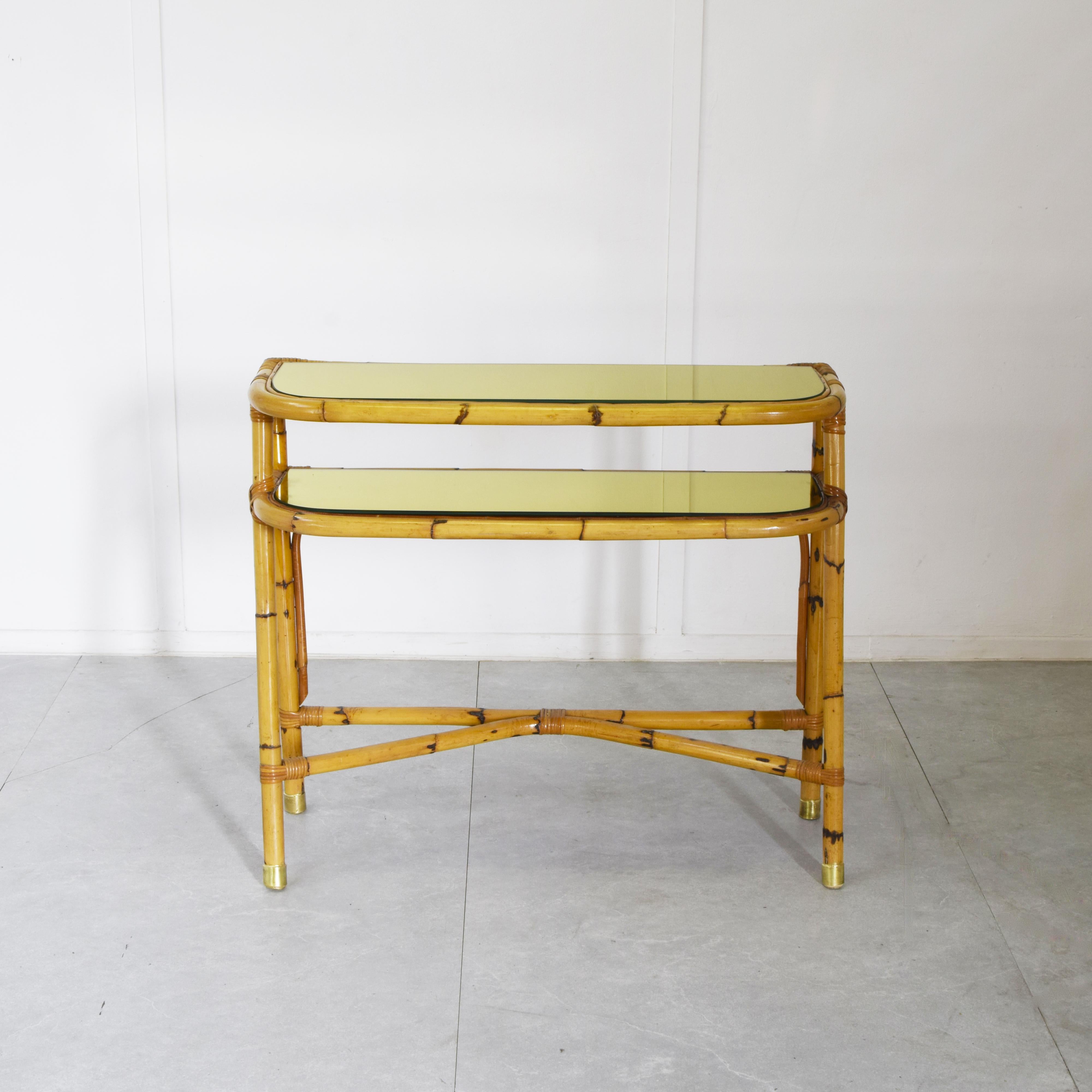 This vintage two-tier console table perfectly embodies the Mid-Century Modern style with strong Hollywood Regency influences. The supporting structure is crafted from authentic natural bamboo that has been curved and bound, typical of Italian