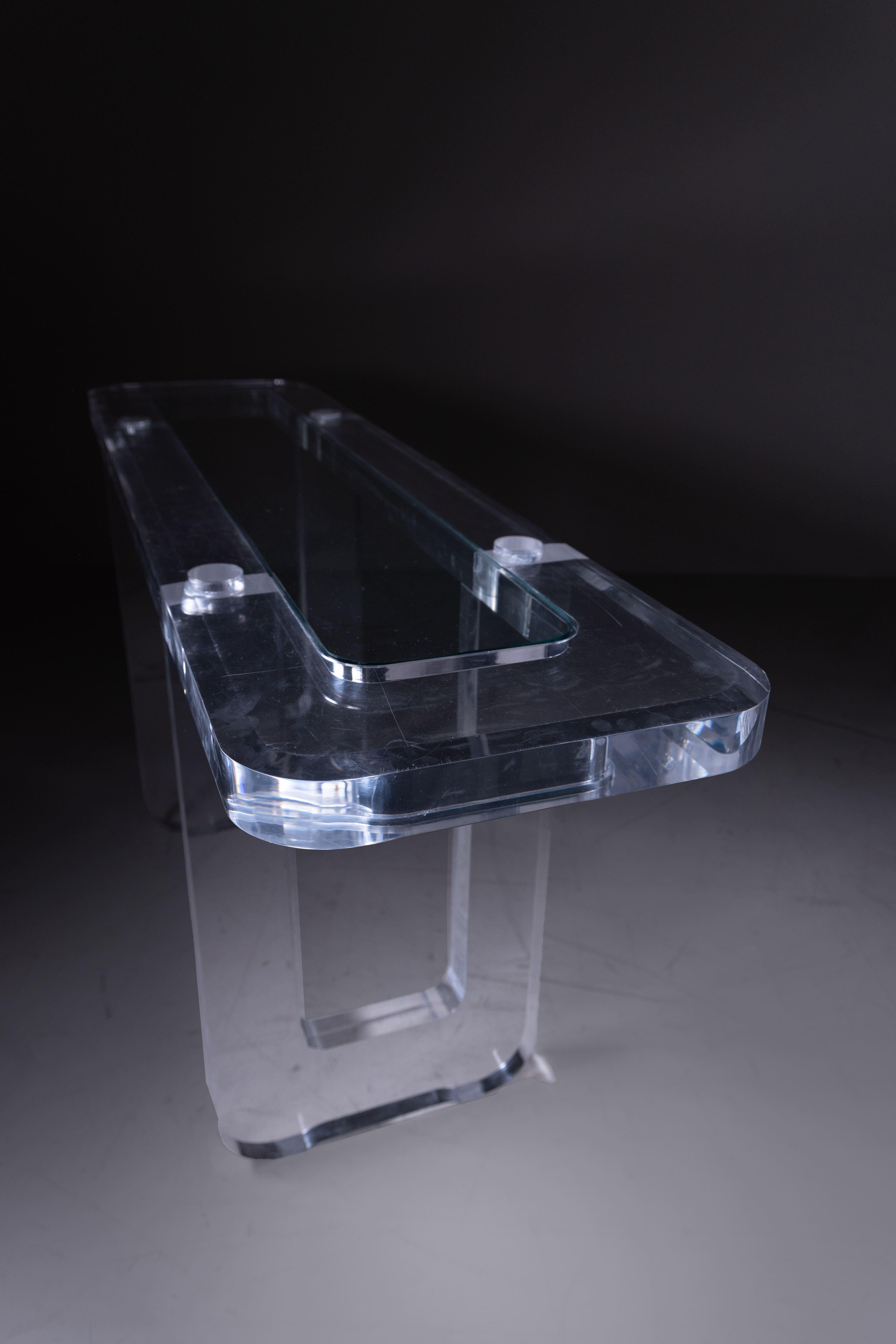 Thick transparent plexiglass console table with glass top, 1980. Elegant and minimalist, this console table is distinguished by its remarkably thick plexiglass frame, which lends stability, solidity and visual lightness at the same time. The glass