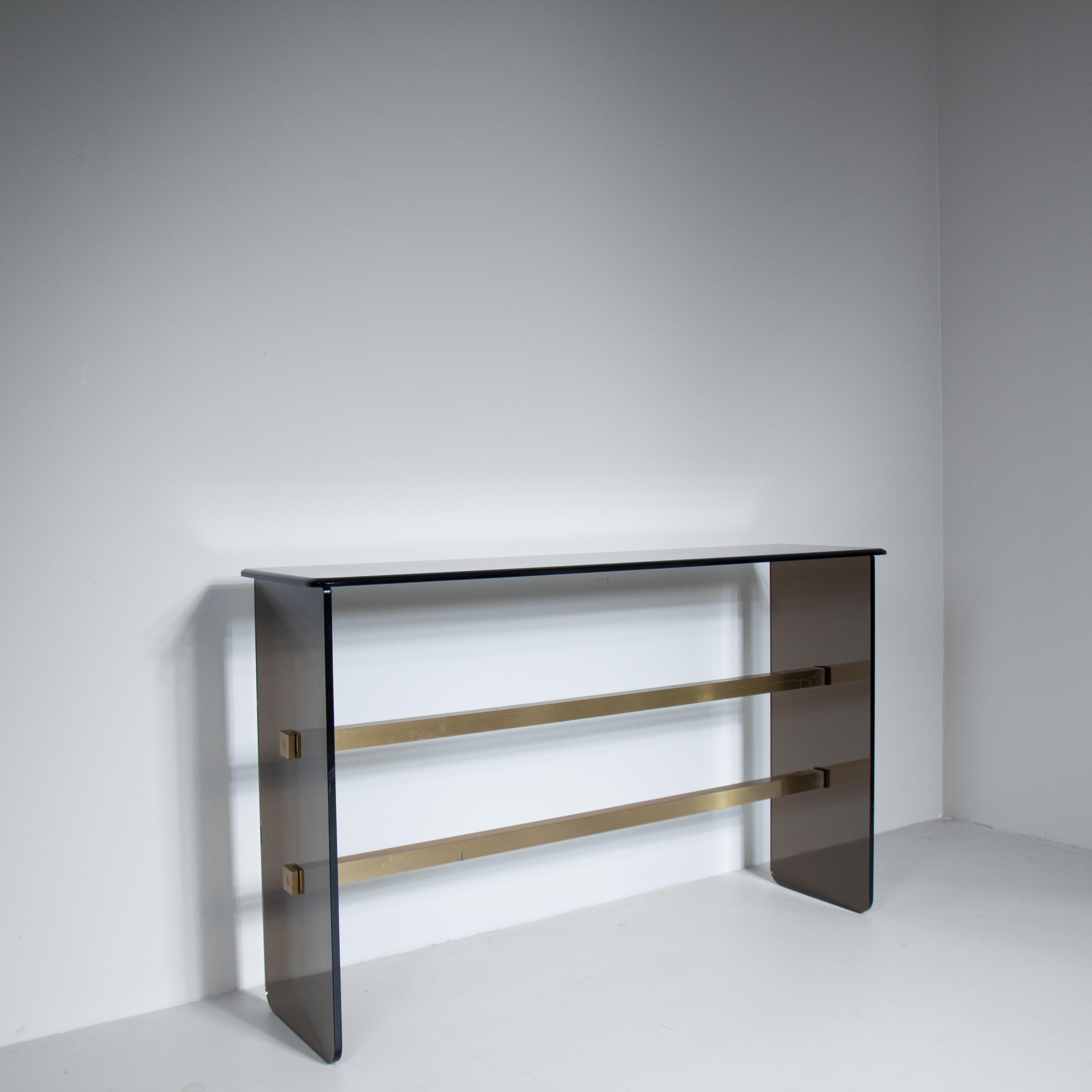 Smoked glass console table with beveled mirror, an elegant example of 1970s design that combines high-quality materials with an essential and refined line. The top and frame are made of smoked glass, offering a sophisticated transparency effect,