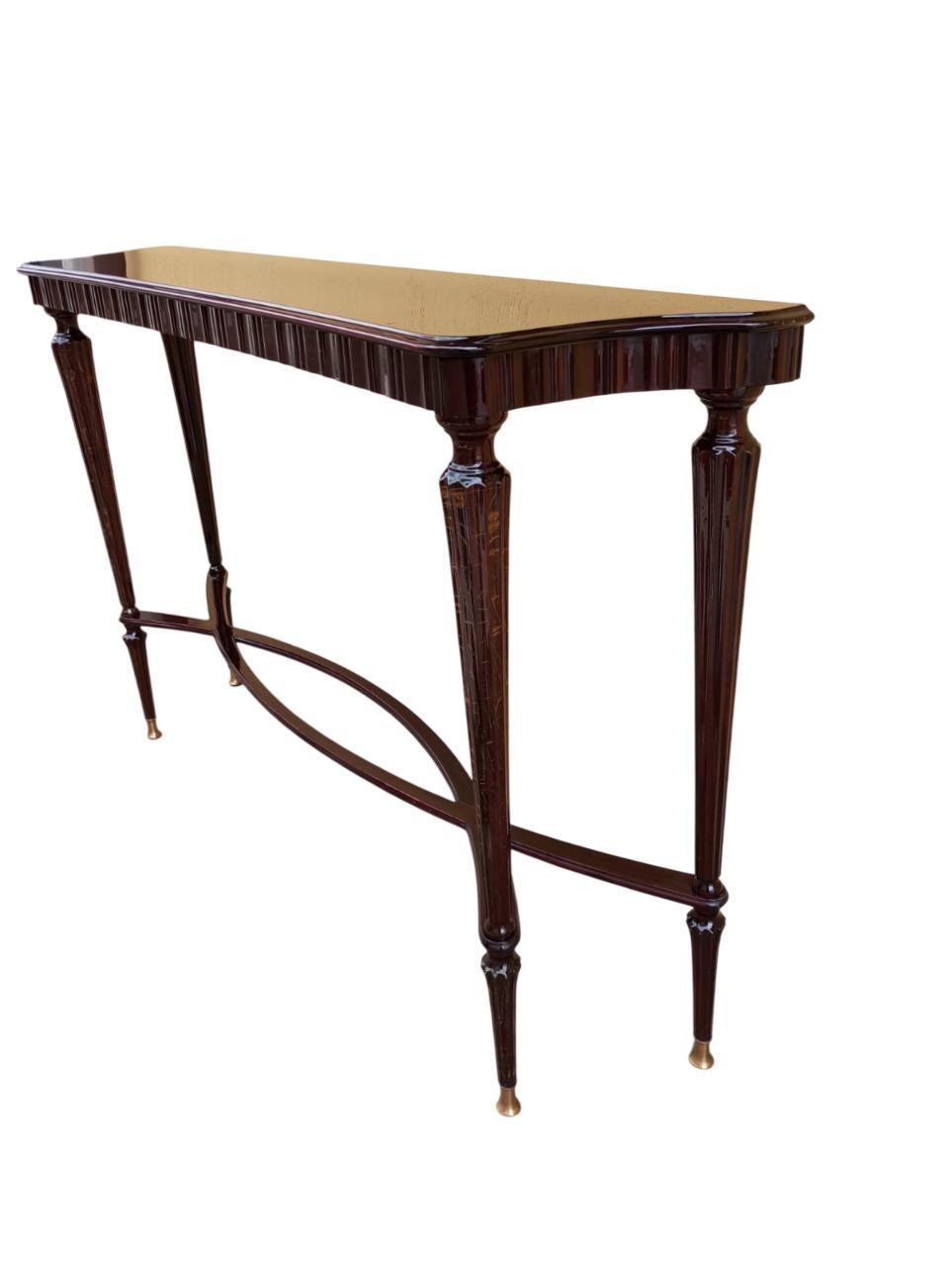 Eleganter Konsolentisch aus Mahagoni, der sich durch ein raffiniertes Design auszeichnet, das sich am Stil von Paolo Buffa orientiert. Die Struktur wird von gerillten Beinen getragen, während das darunter liegende Band ein Kreuzmuster aufweist, ein