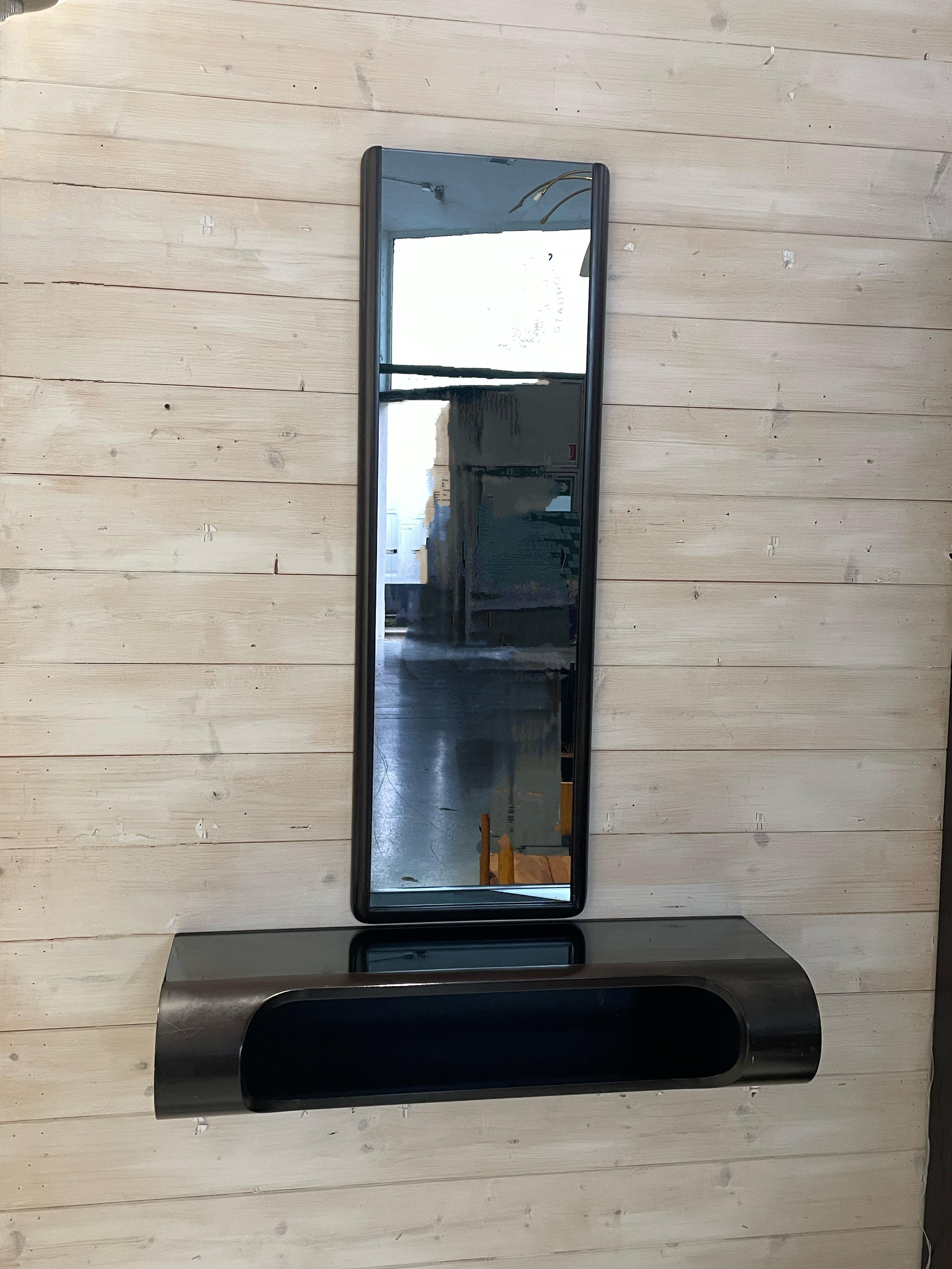 Hanging console table from the 1970s of Italian manufacture.

Lacquered wood frame with glass top and mirror.

The console table with its mirror has a very recognizable design with that of the production period.

With small size it fits well in an
