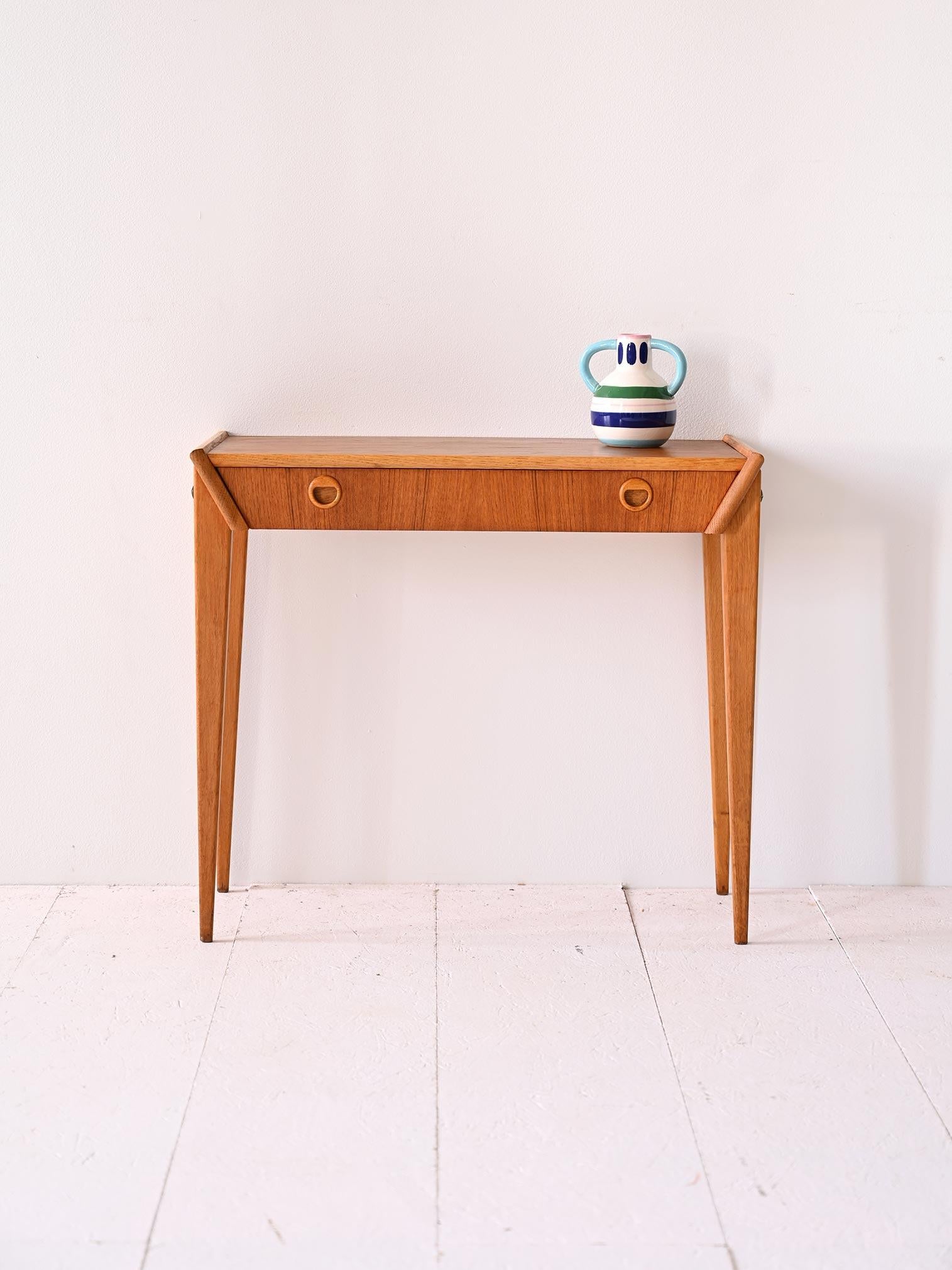 Questo mobile è un esempio perfetto di design scandinavo con un'estetica minimalista e funzionale. Realizzata in legno di teak, presenta linee squadrate e pulite che ne definiscono la struttura.

Il piano è semplice e rettangolare ma il taglio