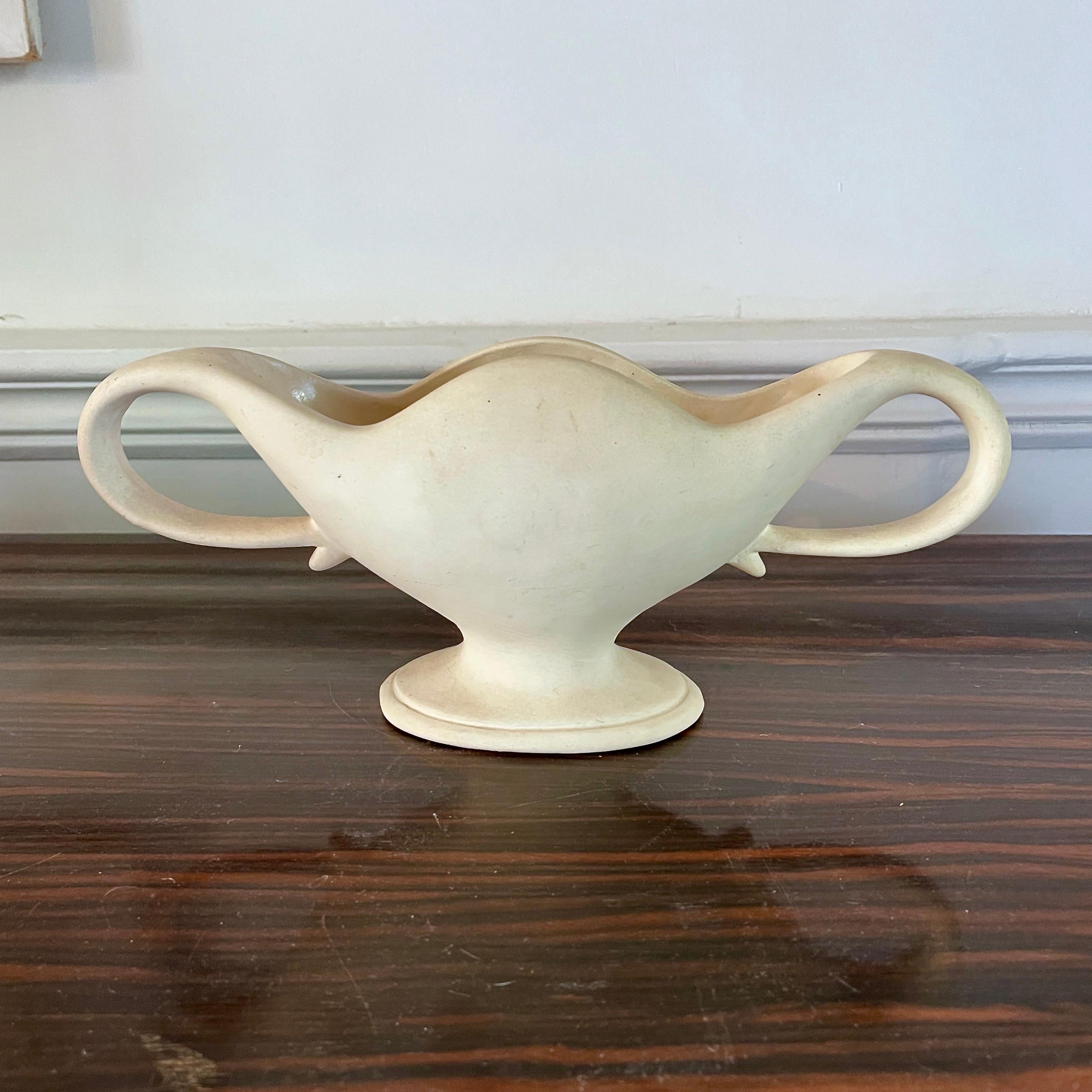 Vaso di Constance Spry per Fulham Pottery, anni '30 circa 

Un bellissimo pezzo di Fulham Pottery con manici curvi e corpo ondulato, rifinito in un ricercato color crema non smaltato, formato da una base ovale con piedistallo. 

Timbro Fulham