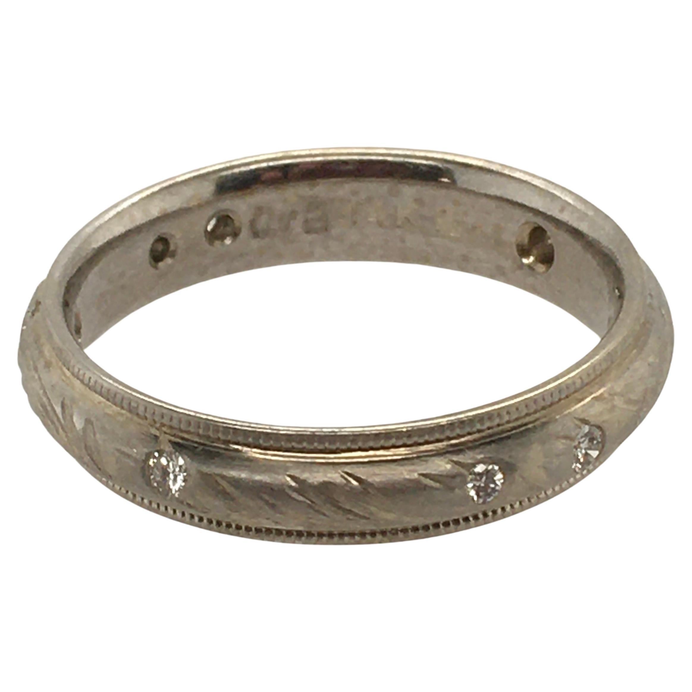 A lovely Constance Wicklund Gildea wedding band: 4mm 14K white gold featuring her sea grass pattern and textured edges.  The ring showcases  8 flush .10TCW diamonds surrounding the band. Maker's mark printed on the interior.  The ring is size 7.