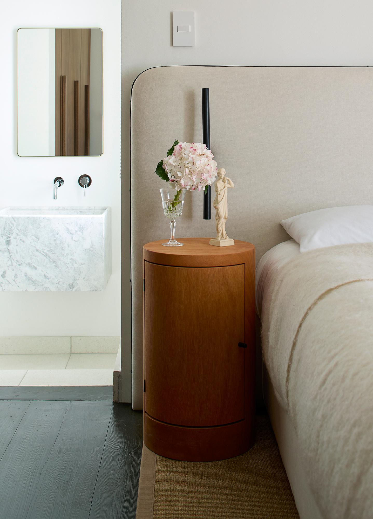 Envisioned by designer Yaniv Chen, the Constant nightstand exudes an air of refined luxury, celebrating the inherent splendor of Iroko wood. Sourced from West Africa, this remarkable timber showcases a captivating honey-colored hue that gracefully