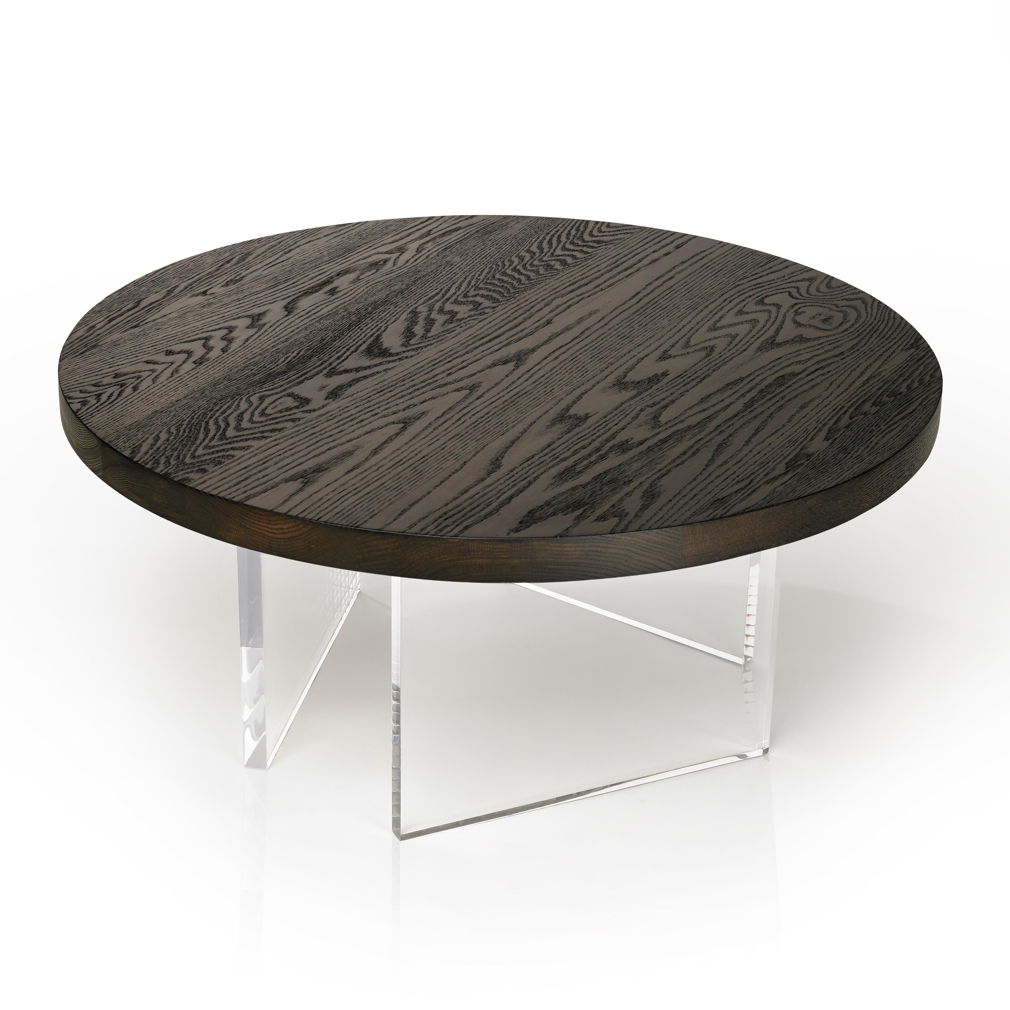 The refined Constantinople Round coffee table in torched oak, using the traditional Japanese shou-sugi-ban technique, provides a sophisticated feel to its space. The tabletop sits on three acrylic one-inch thick legs that allow light to pass through