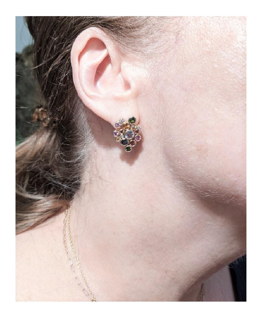 Multi- stone post earrings, each one bezel set with twelve round, colorful gemstones and 3 diamonds in each earring. The gemstones come together to create the Constellation Cluster post earrings in gold. The design is based on a star constellation