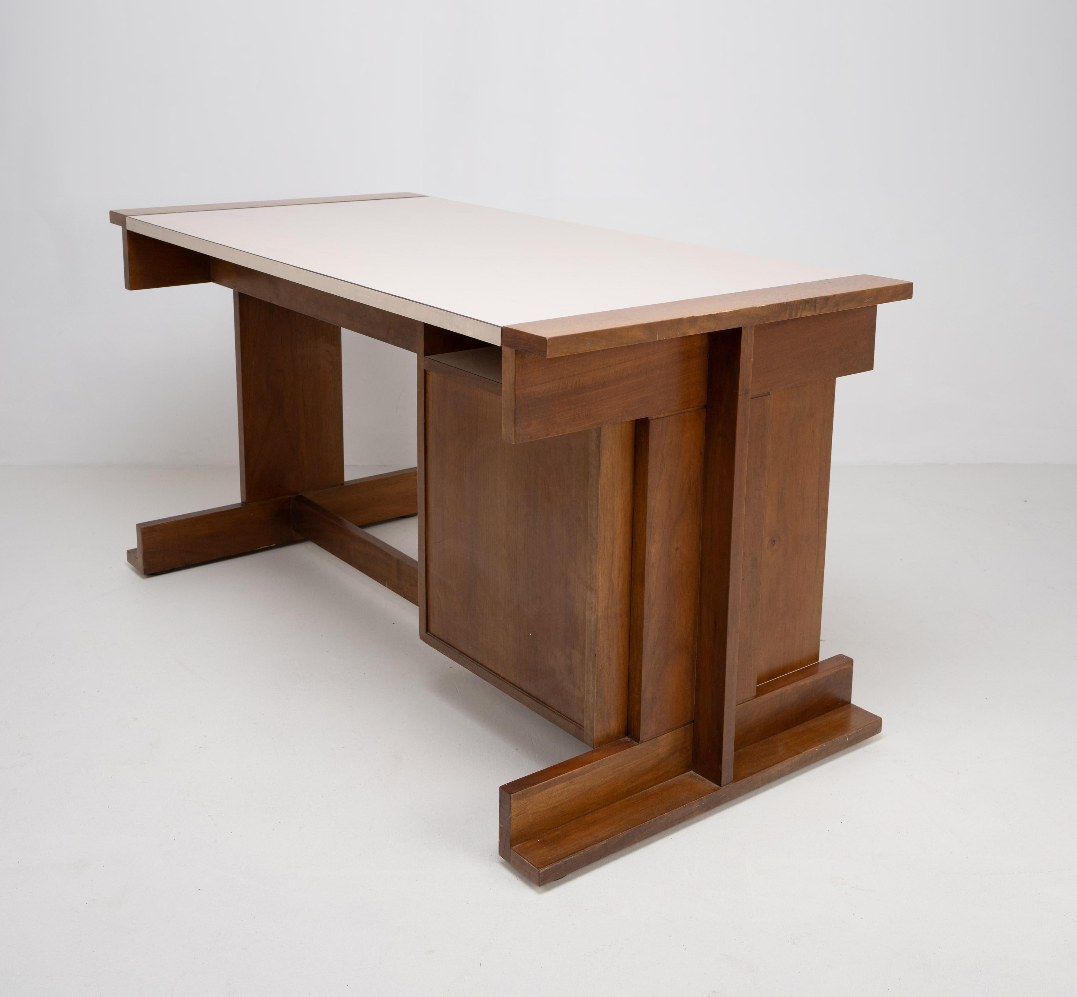 Ein italienischer Schreibtisch aus den 1950er Jahren mit einer Reihe von 4 Schubladen, einer breiteren Schublade und einer cremeweißen Melaminplatte, die von zwei geometrischen H-Rahmen getragen wird. 

Abmessungen (cm, ca.):
Höhe: 74,5
Breite: