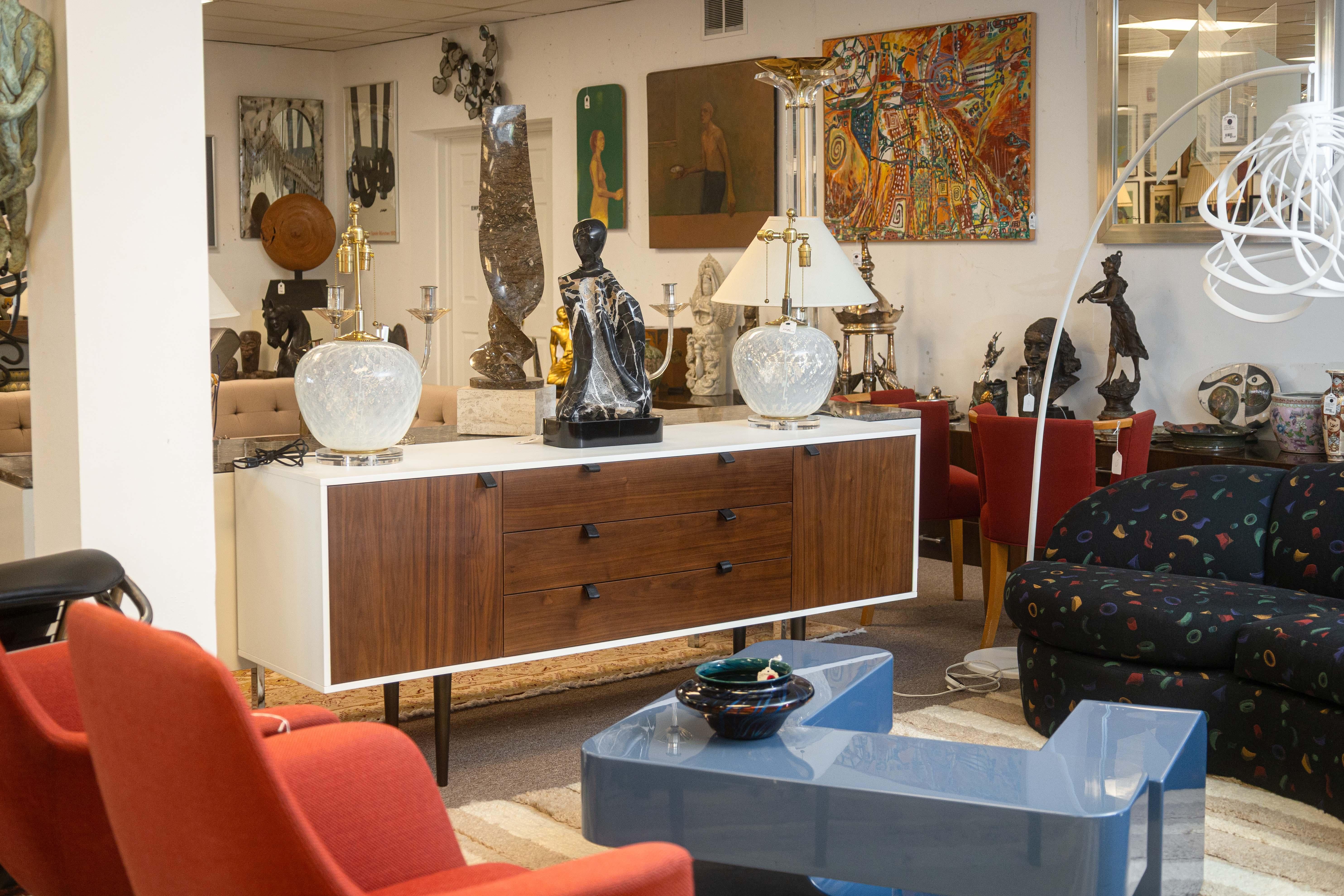 Una credenza moderna e contemporanea. Questo design semplice e moderno è un classico della metà del secolo con un corpo rettangolare e quattro piccole gambe affusolate. Questa credenza ha il corpo in laminato bianco e l'intera superficie è rifinita