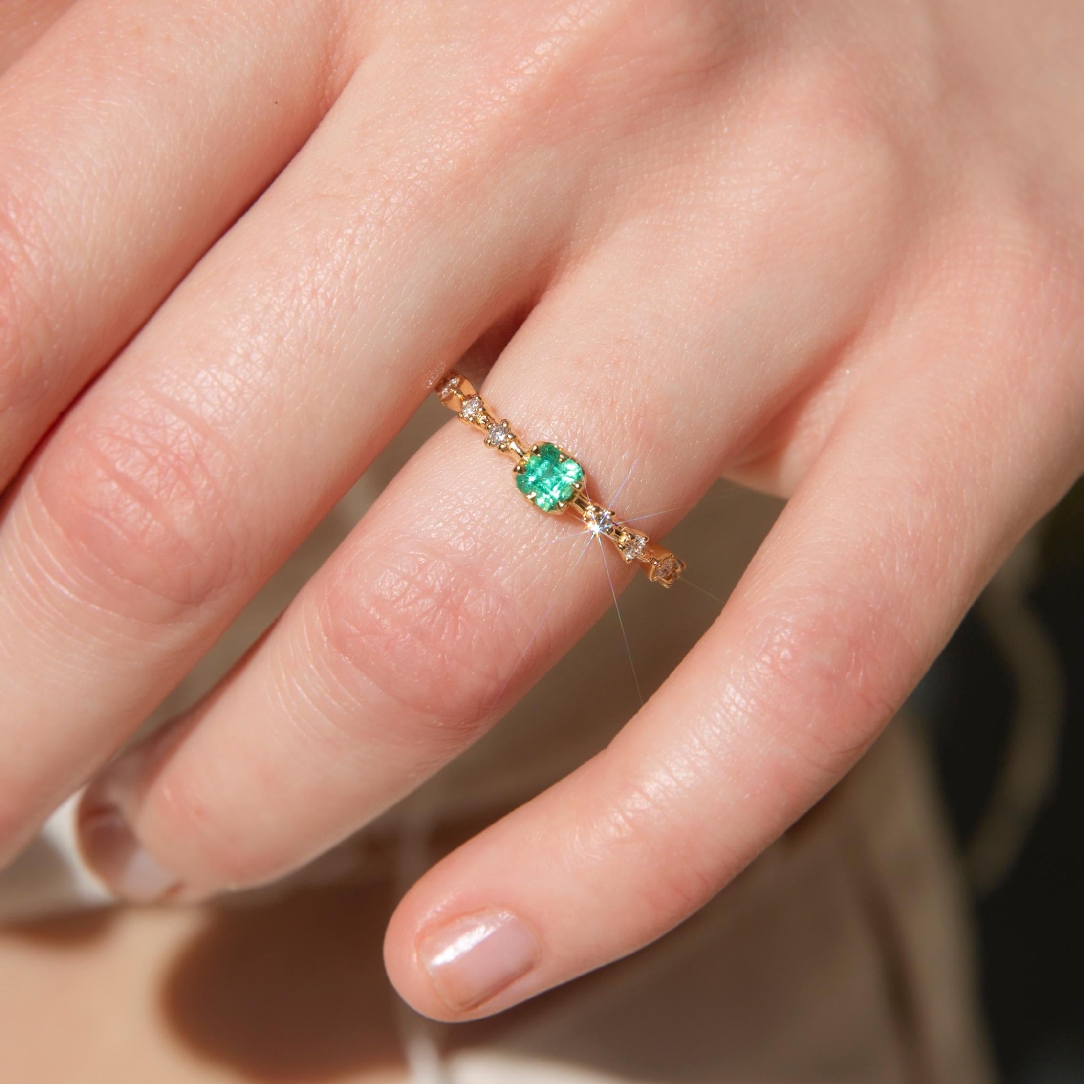 Crafted in 18 carat yellow gold, this delightful contemporary ring holds an alluring natural green emerald flanked by eight glistening round brilliant cut diamonds shimmering in unison. Her name is The Ruri Ring, the perfect ring for stacking with