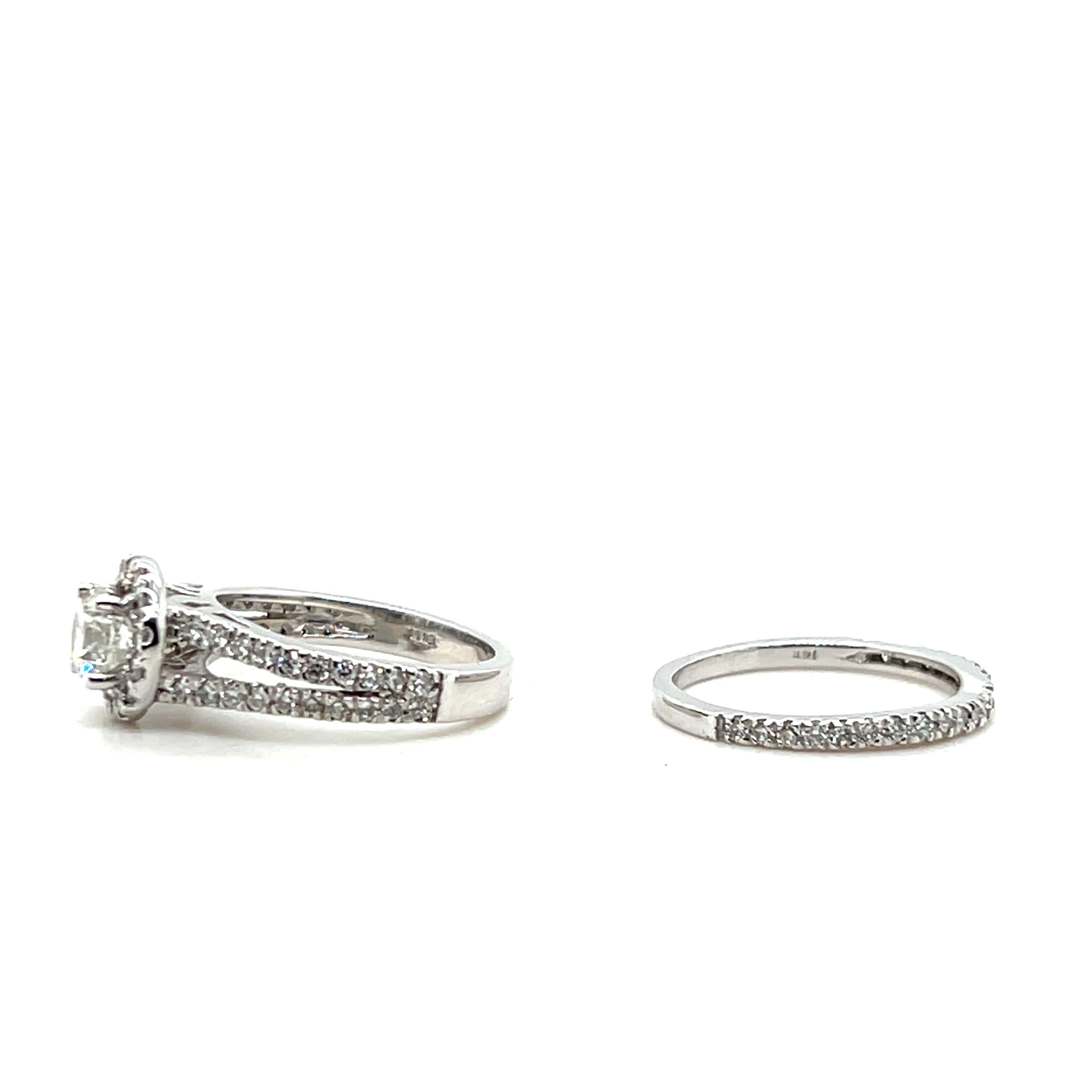 This contemporary 14 karat white gold engagement ring features a round brilliant diamond of approximately 0.60 carats, with H/I color and I1 clarity, surrounded by a shimmering halo. An additional fifty-four round brilliant diamonds, totaling