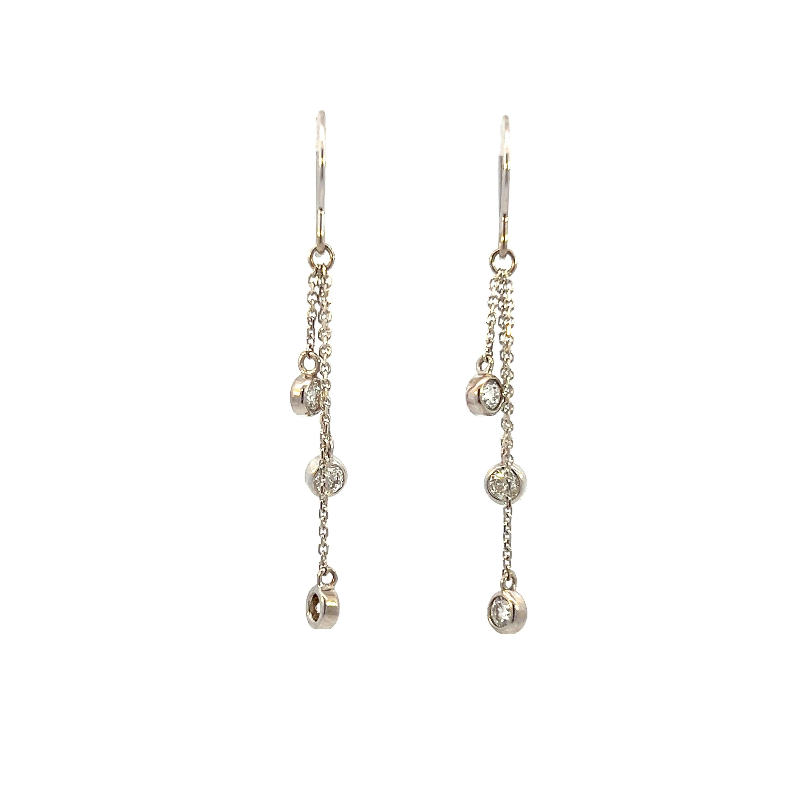 Questi orecchini contemporanei in oro bianco 14 carati offrono un design elegante e minimalista con un sottile scintillio. Ogni orecchino con gancio da pastore è incastonato con tre diamanti rotondi taglio brillante, per un totale di circa 0,60