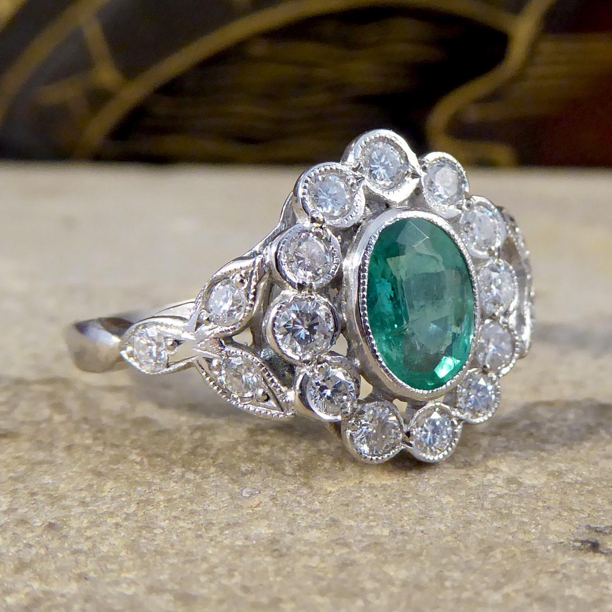 This lovely contemporary Emerald and Diamond ring has been crafted with a 0.75ct mesmerising green Emerald centre, surrounded by 12 modern brilliant cut Diamonds. Using larger Diamonds in this cluster ring allows there to be spacing between the