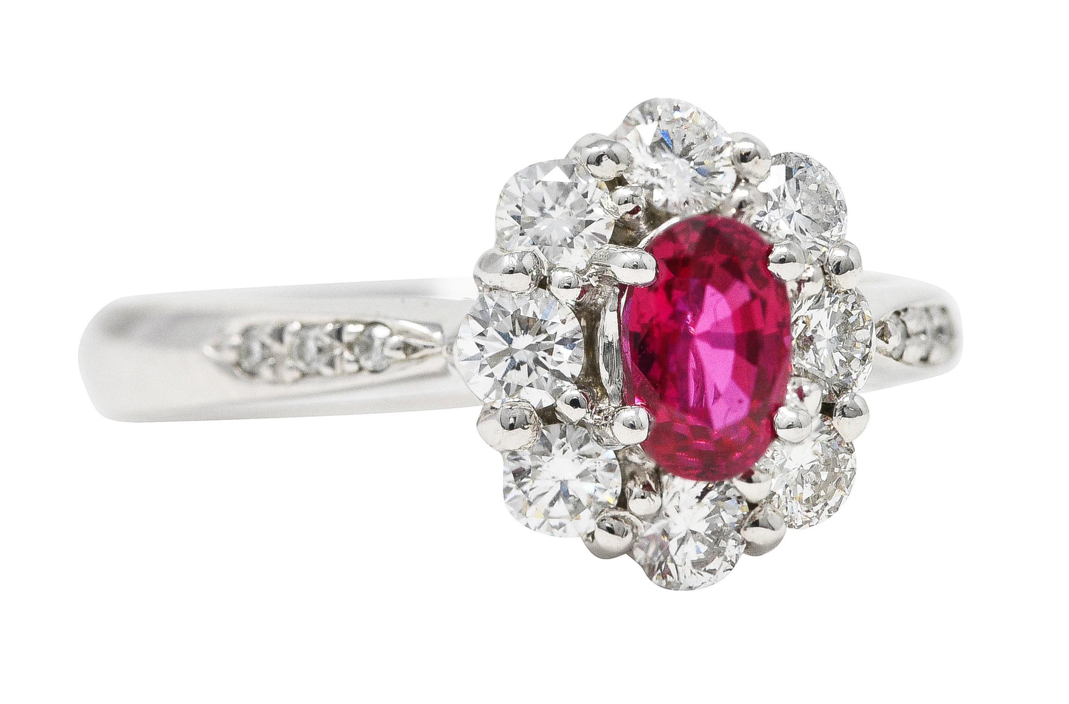 Centering an oval cut ruby weighing 0.60 carat total - transparent slightly purplish-red. Prong set with a halo surround of round brilliant cut diamonds. With additional diamonds bead set in shoulders. Weighing 0.64 carat total. Completed by tapered