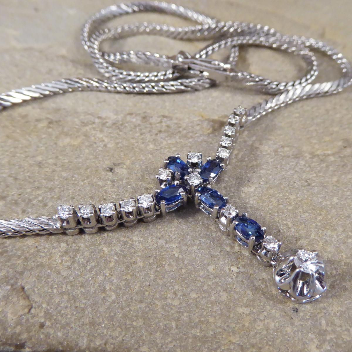 This lovely contemporary necklace with a unique thicker double set S link chain in 14ct White Gold. The necklace features a Sapphire and Diamond cross shaped drop. A detailed and decorative necklace that sits beautifully on the neckline.

Sapphire