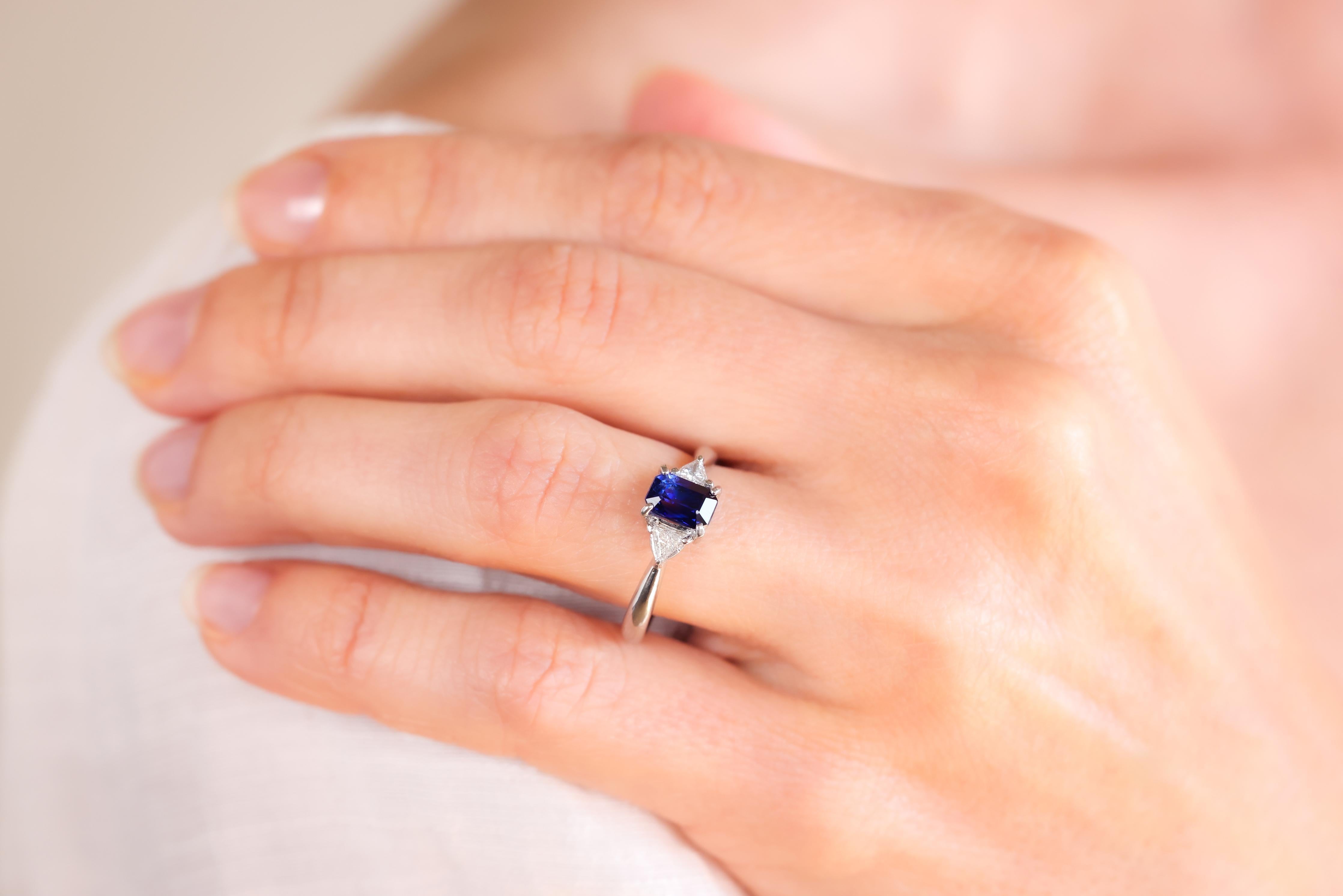 Center Stone: Sapphire
Cut: Emerald
Weight: Approximately 1.28 Carats
Color: Blue
Accent Stone: 2 Diamonds
Cut: Trillion
Weight: Approximately 0.16 Carats
Color: F
Clarity: I1
Metal: Platinum
Era: Contemporary
Circa: 2010s
Hallmarks: Pt900
Size: 6