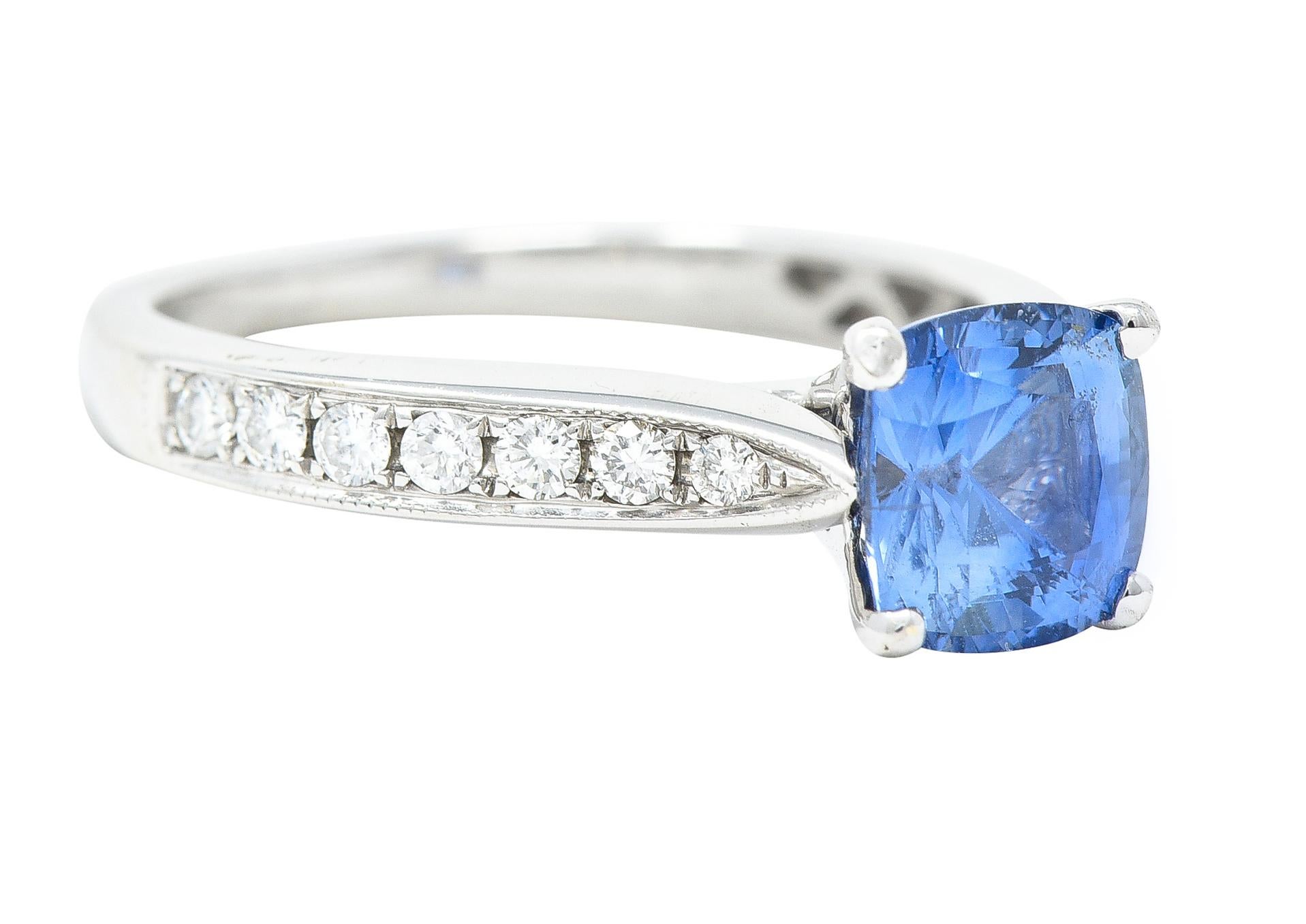 Centering a cushion shaped mixed cut sapphire weighing approximately 1.20 carats total - transparent light blue. Prong set in basket and flanked by tapered cathedral shoulders. Bead set with round brilliant cut diamonds. Weighing approximately 0.18