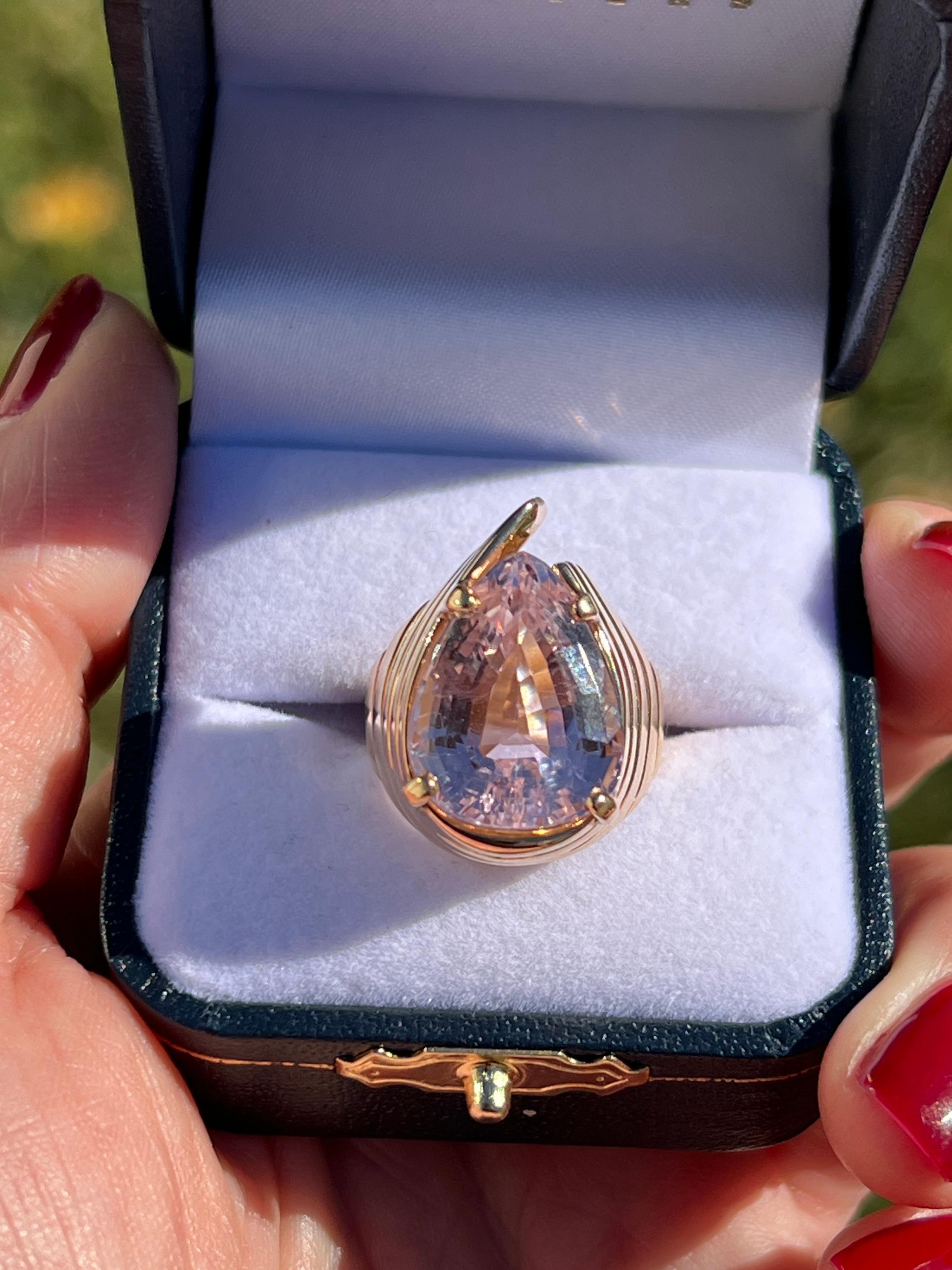 Embrace vintage sophistication with this 1980s 14 karat yellow gold ring, showcasing a stunning 13.86-carat pear-shaped light pink kunzite. The swirling shell-inspired design beautifully complements the soft glow of the kunzite, making this ring a