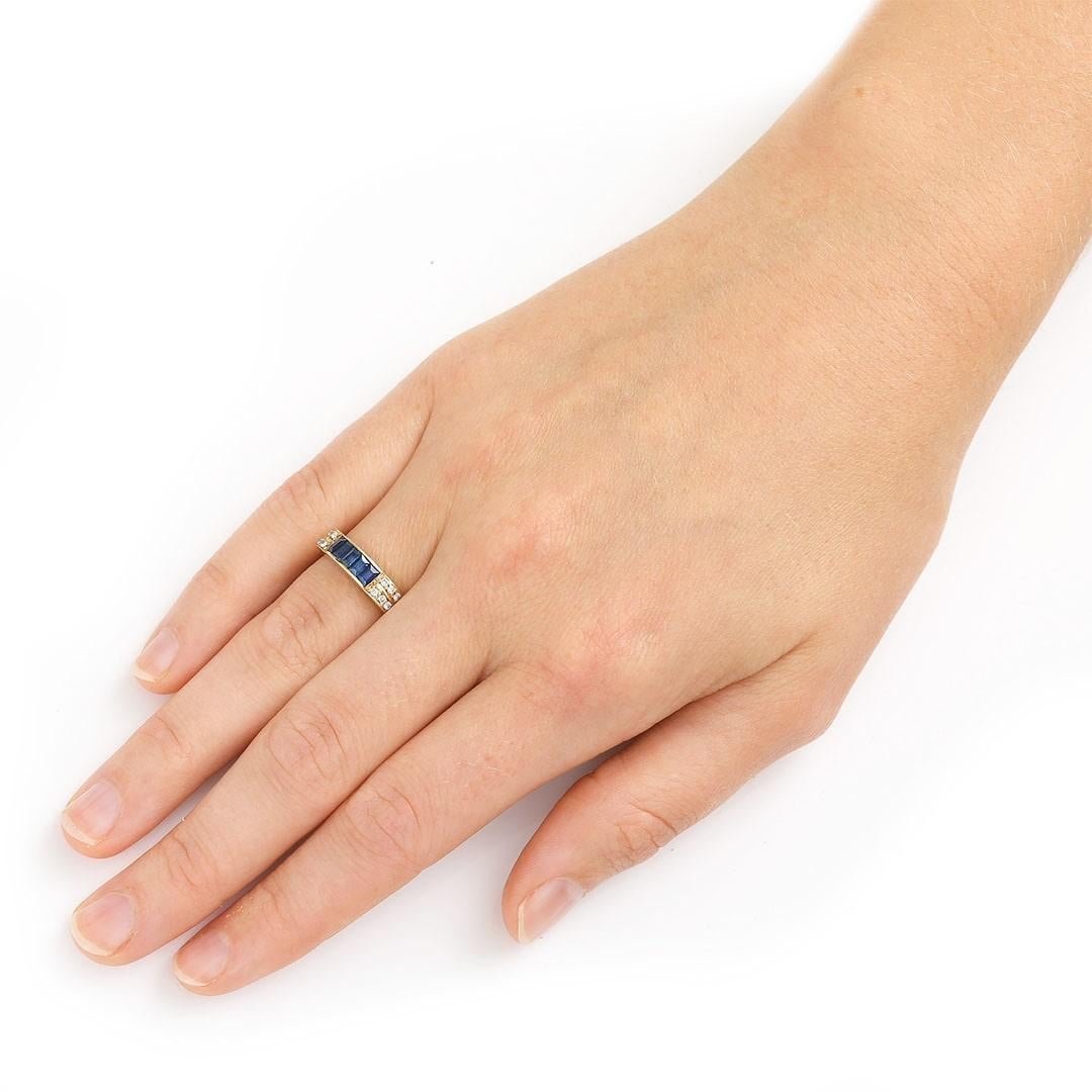 A stylish 14ct yellow gold baguette cut blue sapphire and diamond eternity ring that works with both vintage and contemporary designs. The ring is channel set with bright, deep blue baguette cut sapphires with the shoulders accented with brilliant
