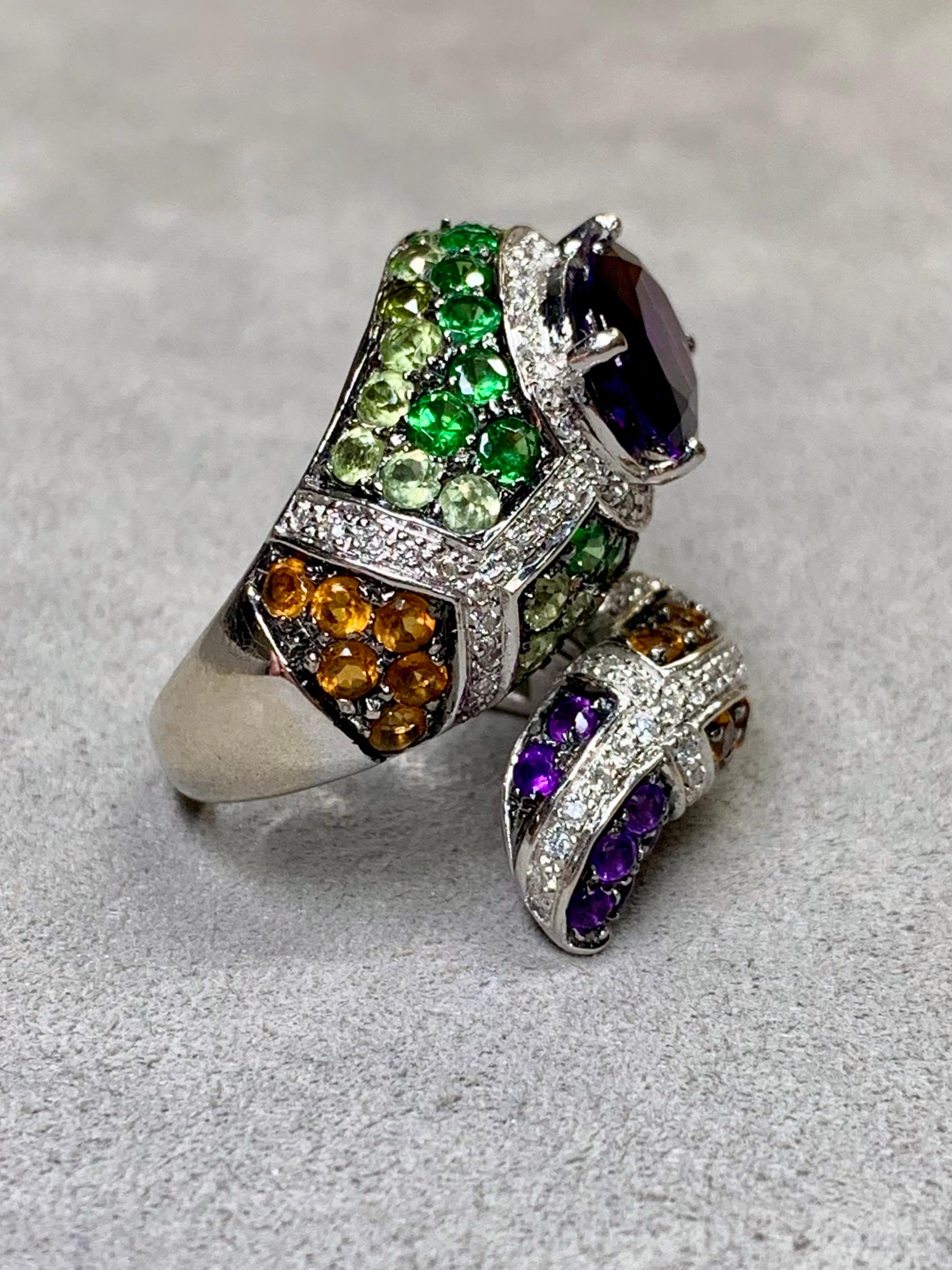 
A nicely done ring and whimsical in its design. It has been crafted in 14K white gold and set with approximately .88ctw in H-I color si1-2 clarity diamonds as well as peridot, tsavorite, citrine and one larger central approximately 3.50ct oval