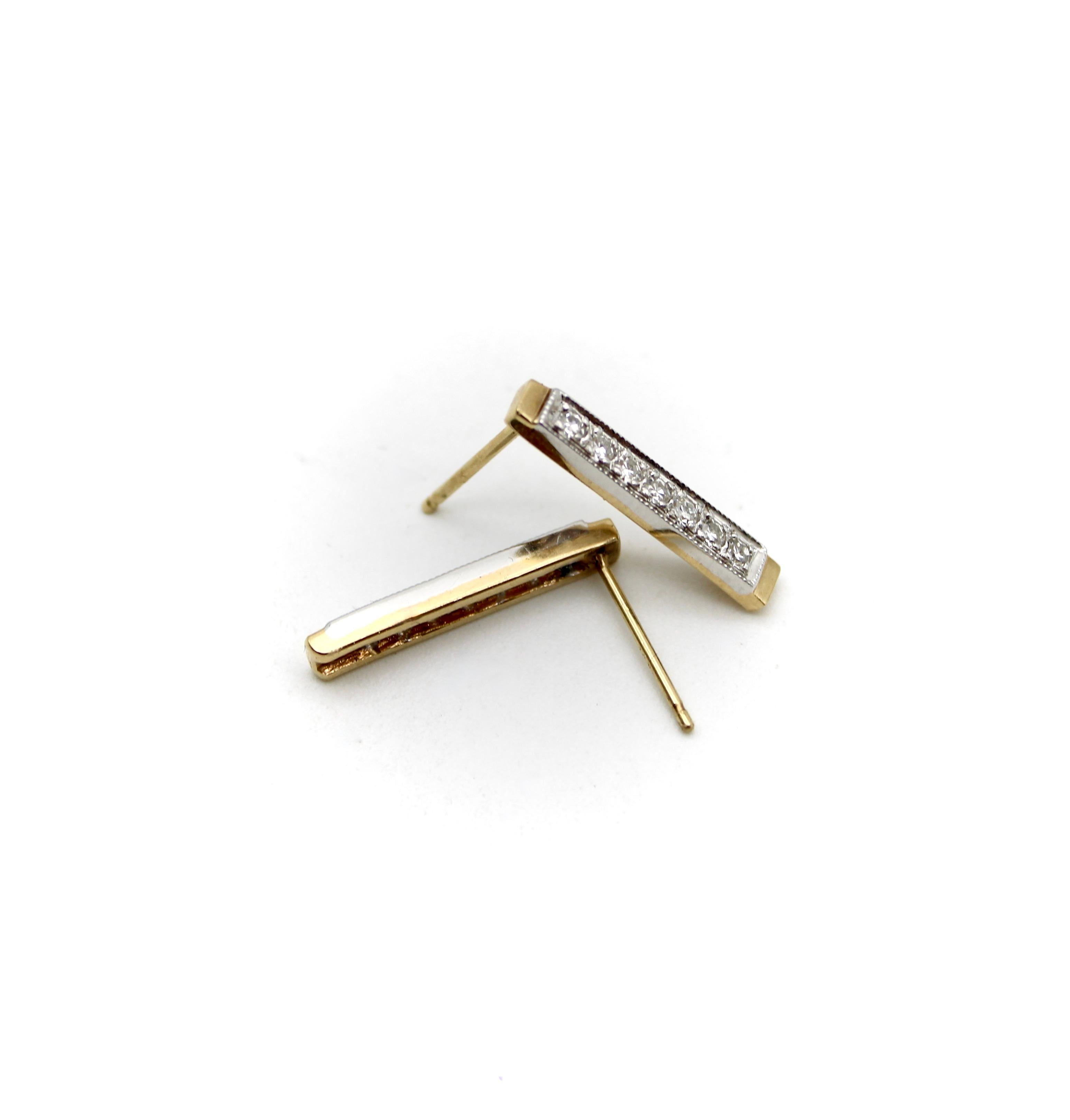 This is an elegant pair of diamond bar earrings. The earrings feature 14 karat yellow and white gold. They have angular lines and a retro, bar design with a line of bead set single cut diamonds. These earrings feature milgrain work along the edges