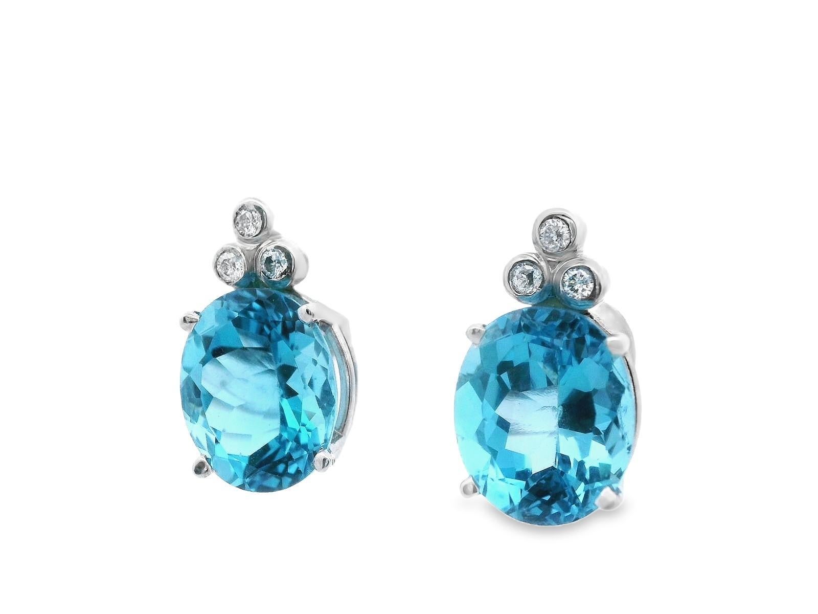 This is a beautiful pair of contemporary earrings made in 14k yellow gold and featuring both soft sky blue topaz and white firey diamond. Each individual earring features three round cut, Si1 clarity, H color diamonds as well as a large 6 ct, oval